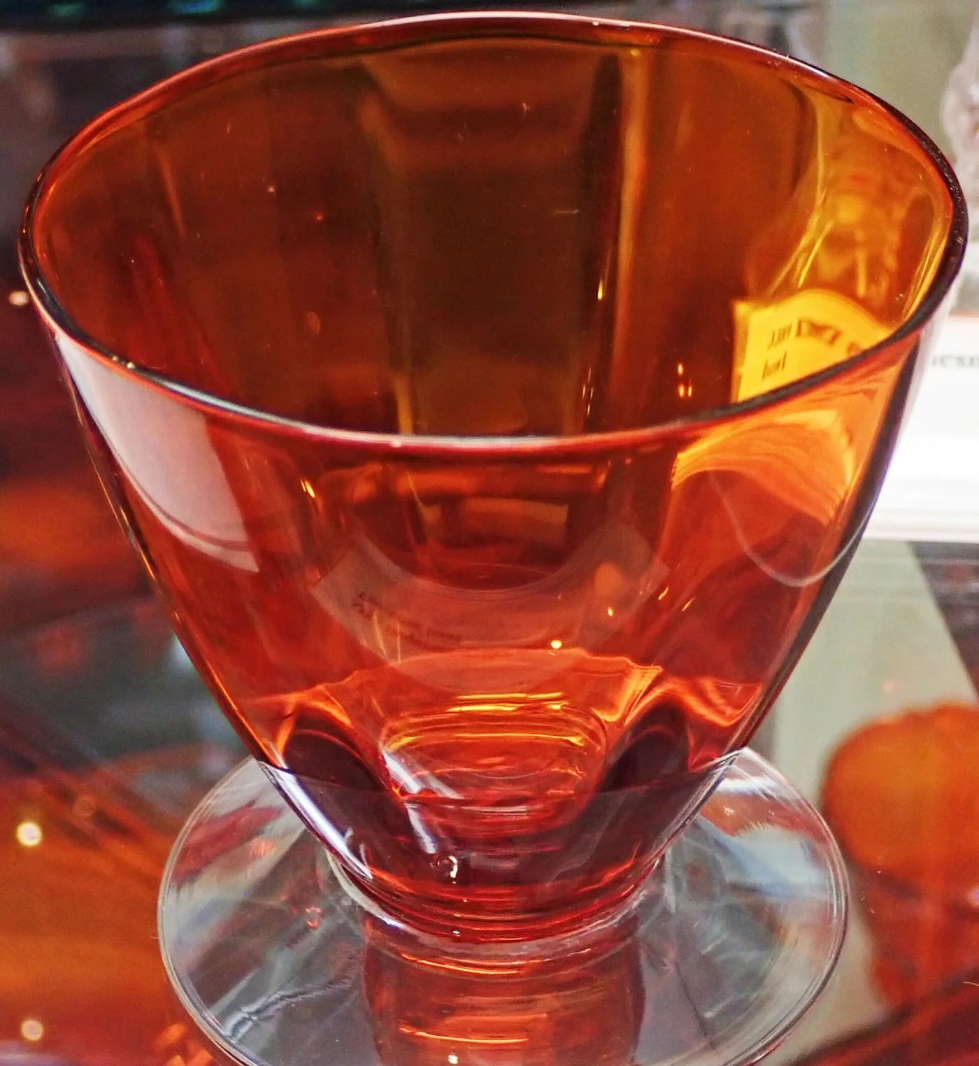 Deep red-orange glass bowl with a fluted body, standing on a clear foot