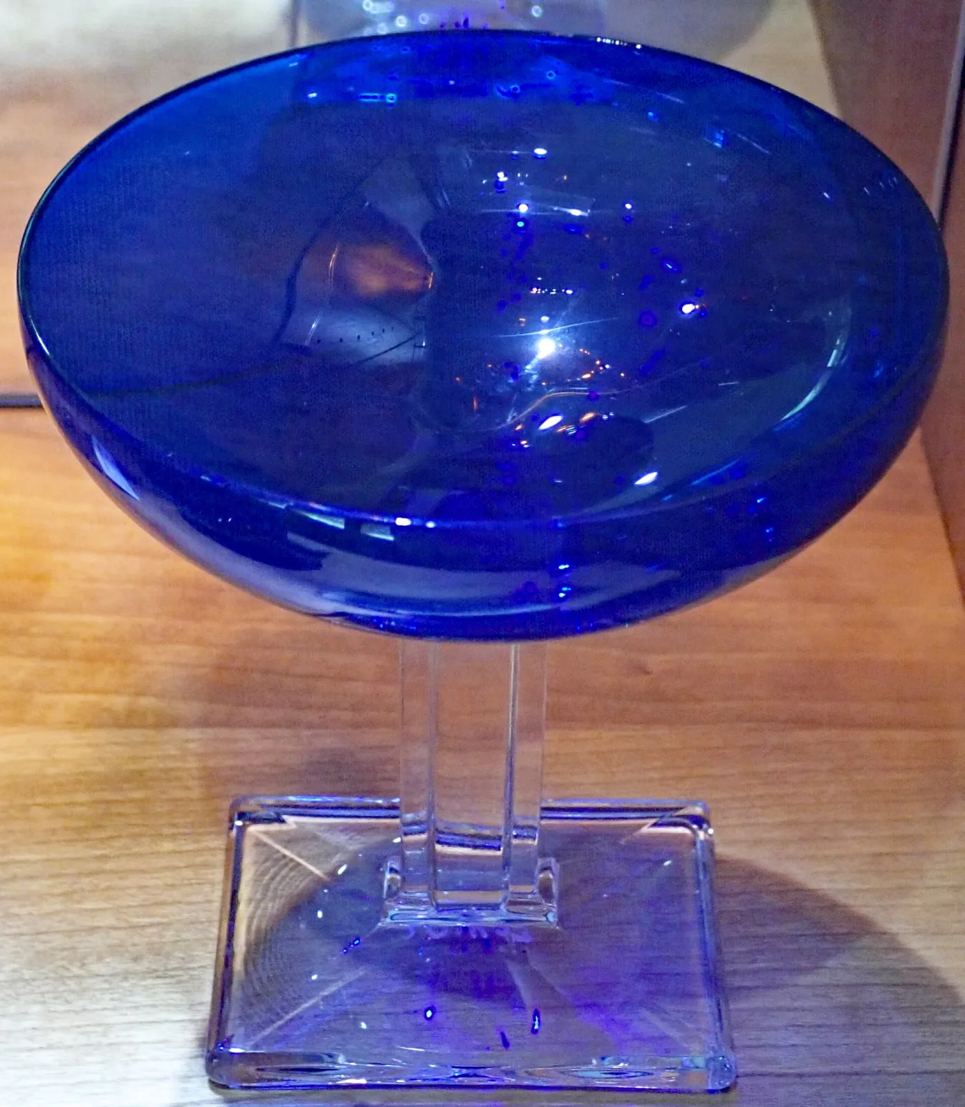 Champagne glass with a deep blue bowl on a clear rectangular stem and square foot