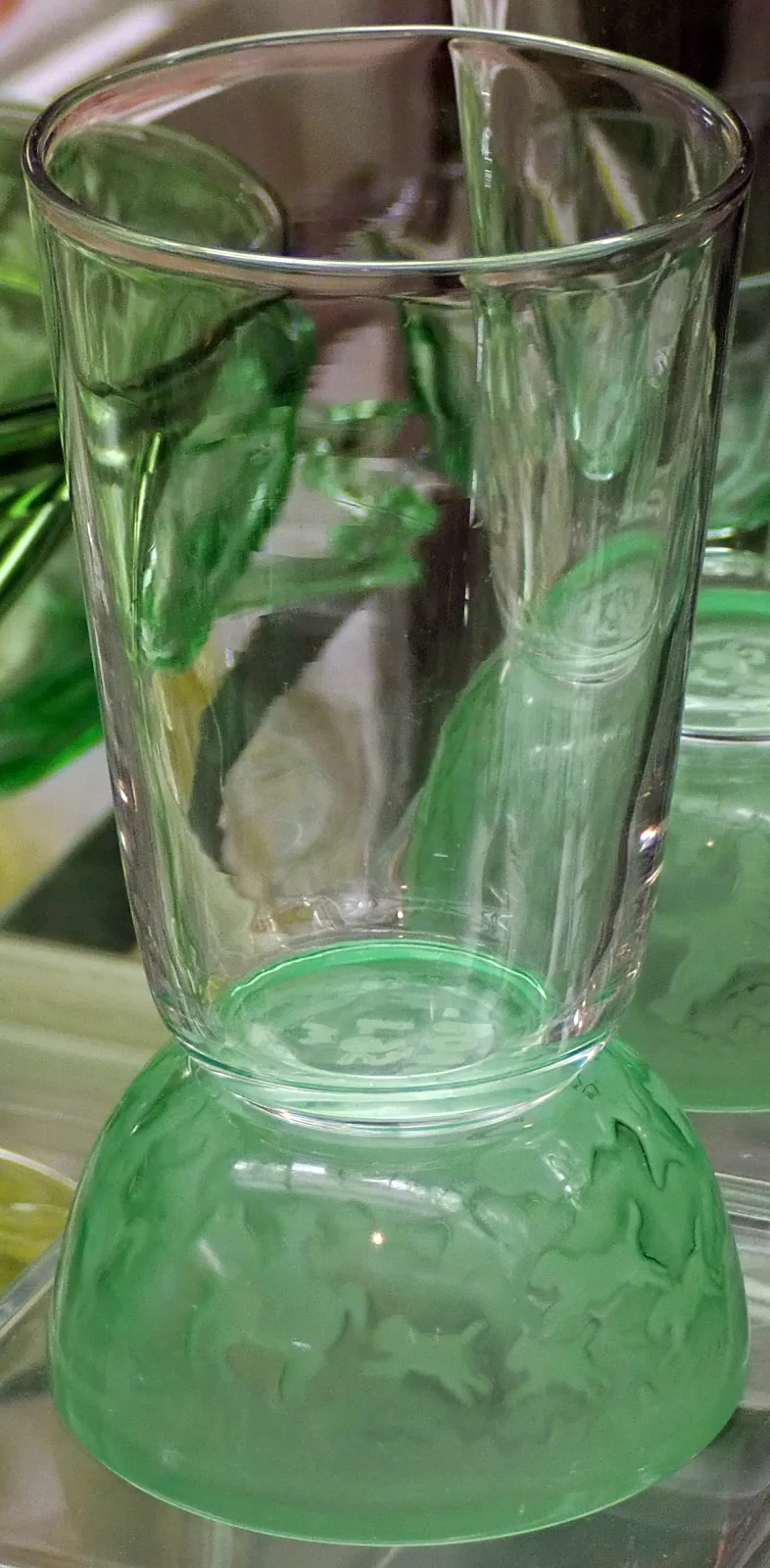 Cocktail glass with a plain clear bowl set on a green domed foot moulded in relief with running horses and riders