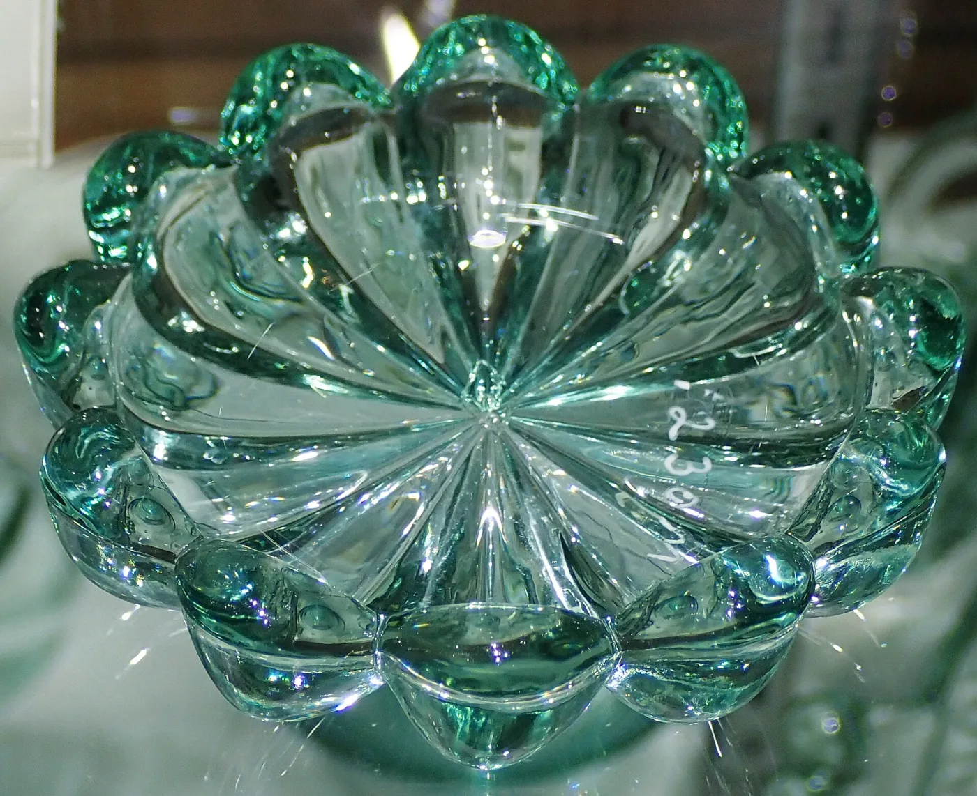 Round pale blue-green pressed glass ashtray with a scalloped rim of short rounded ribs