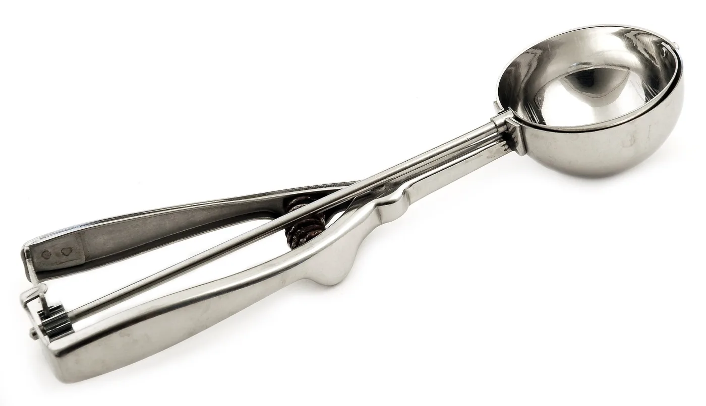 Squeeze-handle ice cream disher seen from above, showing the round bowl, the two-piece handle and the coil spring at the pivot