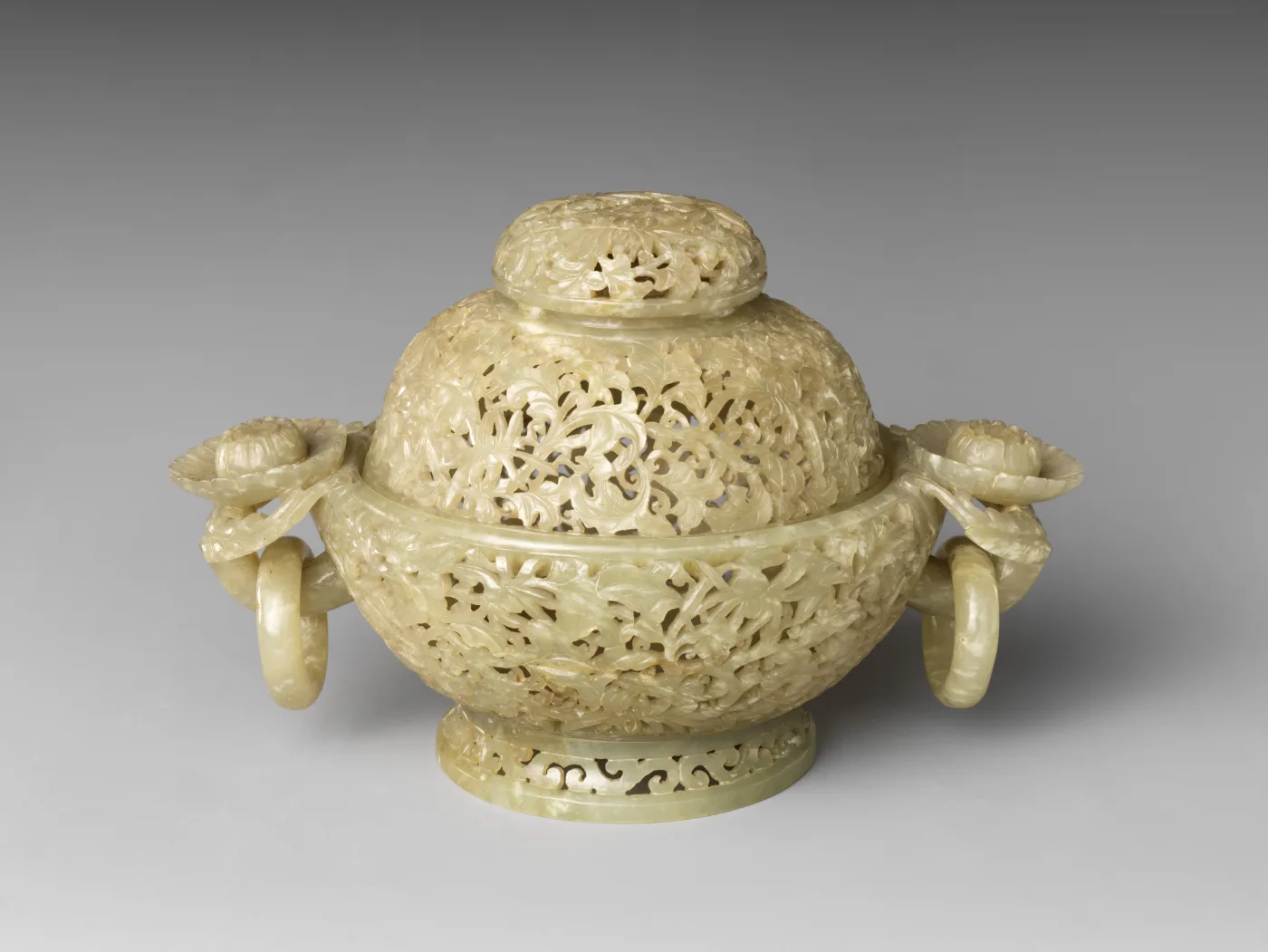 Covered pale yellow-green jade censer pierced all over with openwork foliage, a loose ring hanging from a flower boss at each side