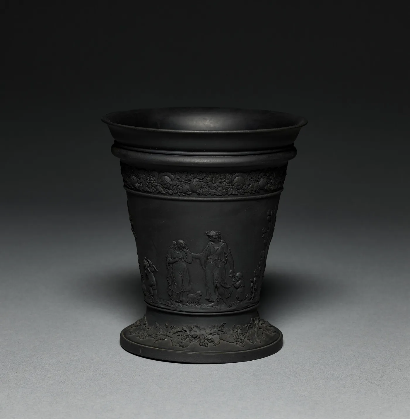 Wedgwood black basalt jardiniere with a flaring rim, a relief frieze of classical draped figures around the body and further relief bands on the stepped spreading foot
