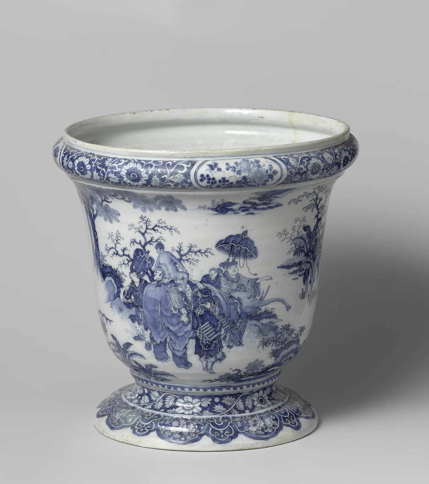 Delft blue and white cache pot of about 1680 on a spreading foot, painted with a landscape containing an elephant with a rider, figures holding a parasol, and rocks and trees