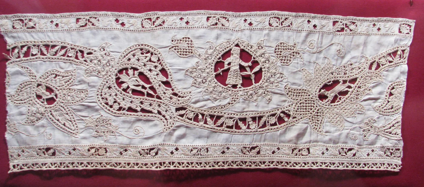 Long narrow band of cream linen worked with square cutwork panels alternating with geometric needle-lace fillings, finished along one edge with a row of small pointed scallops