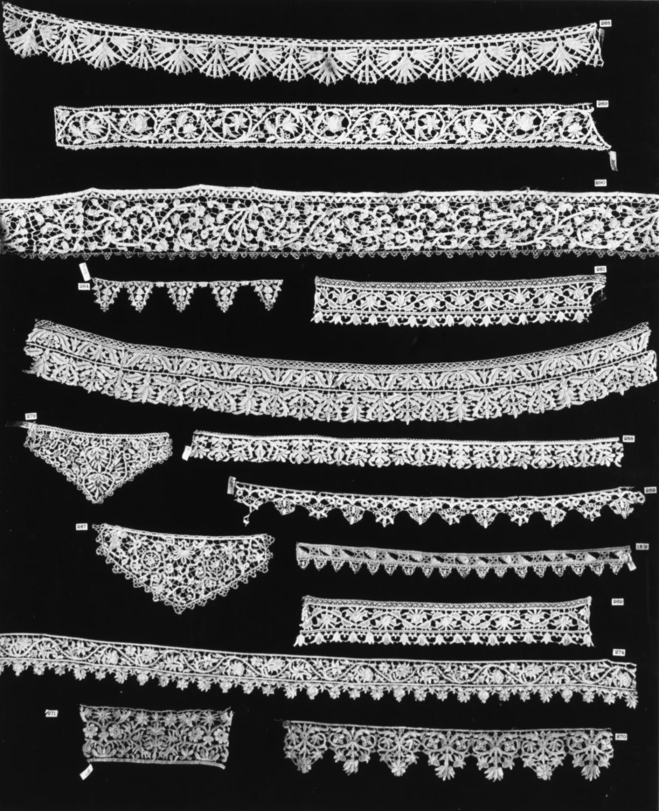 Rectangular fragment of cream lace with a bold repeating pattern of scrolling foliage and formal flowerheads, the edges irregular where it has been cut from a larger piece