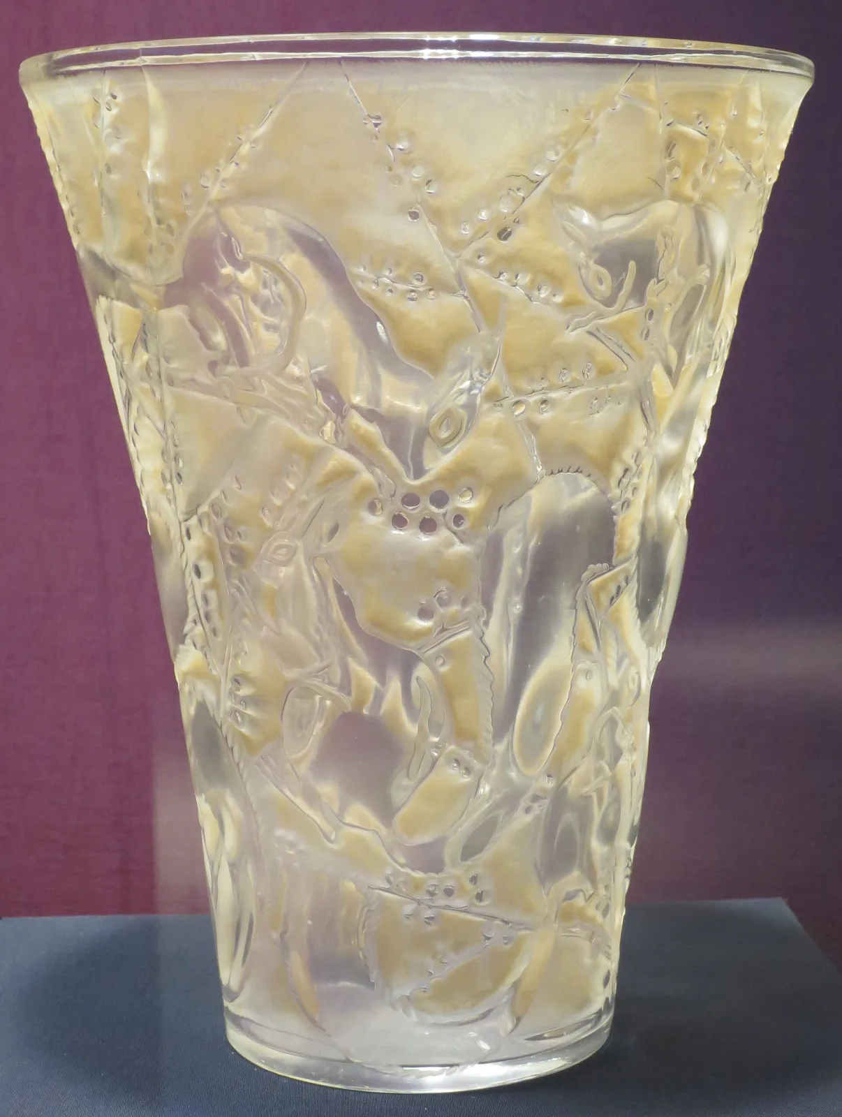 Flared conical vase moulded with squirrels among leafy branches, the recesses of the design filled with a warm brown-amber tint against clear glass