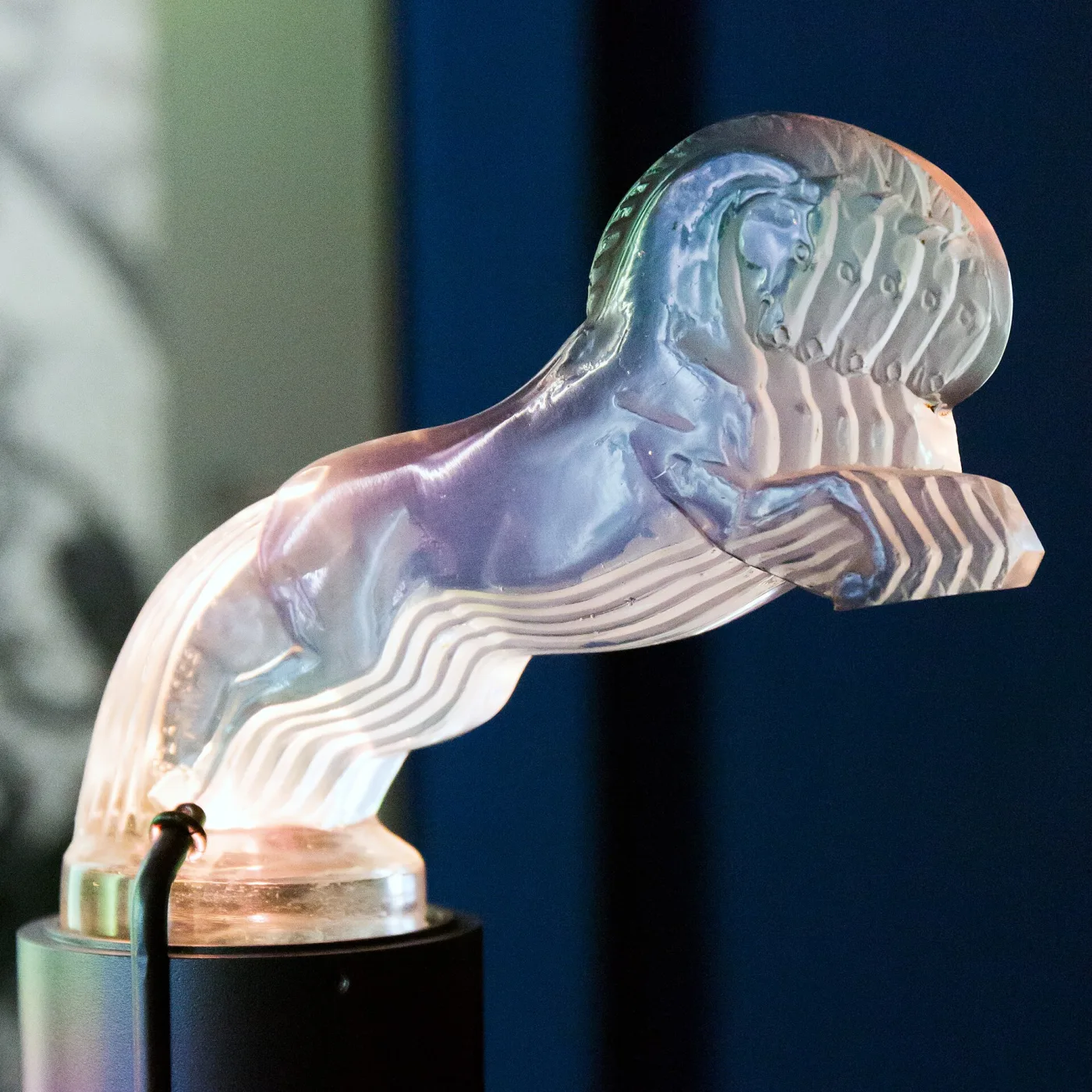 Glass plaque moulded with five galloping horses in relief, lit from below so the glass carries bands of colour