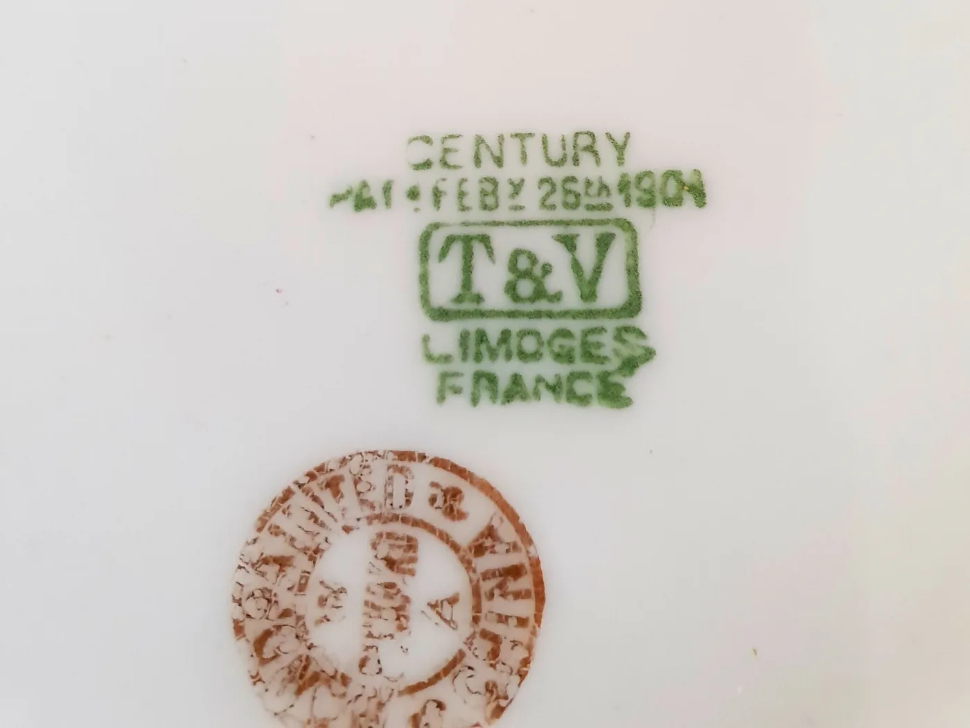 The same green T&V factory stamp with a second darker circular mark printed below it, over the glaze