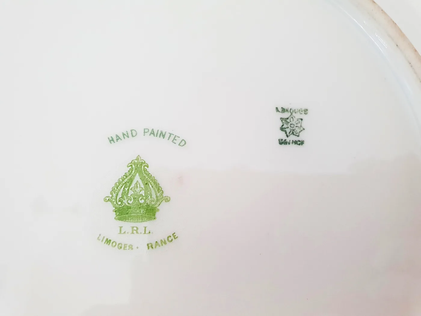 Two green marks on a porcelain plate base: a small factory stamp and a larger crowned mark reading Hand Painted L.R.L. Limoges France
