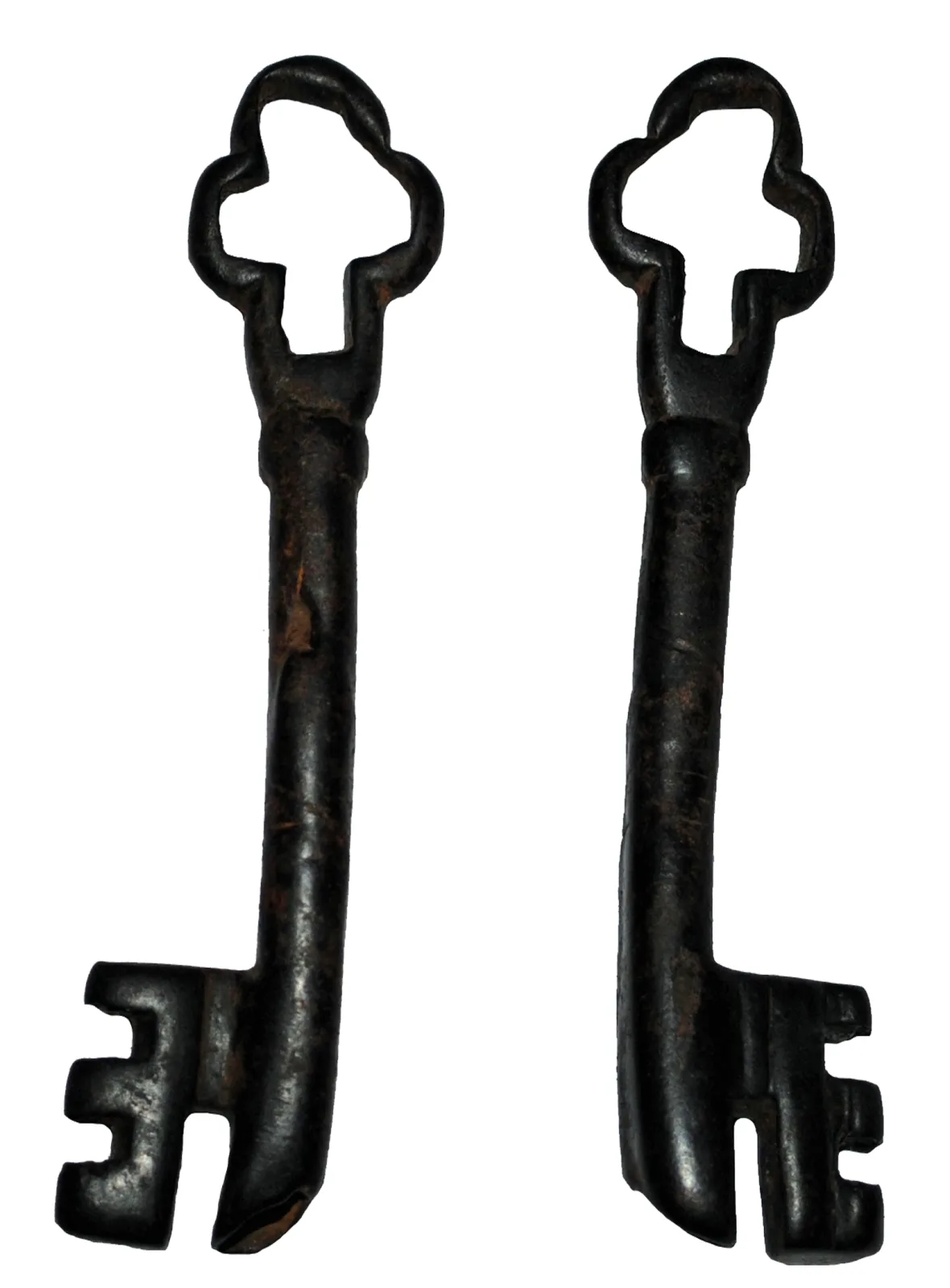 Front and back views of a copper-alloy medieval key with a lobed trefoil bow, a plain shank and a bit cut with several rectangular notches, the metal a dark green-brown