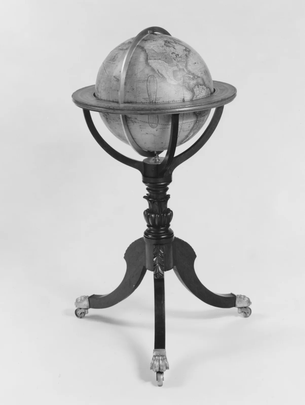 Terrestrial globe mounted in a horizontal ring and half-meridian, supported on a slender turned column with three splayed legs ending in small castors