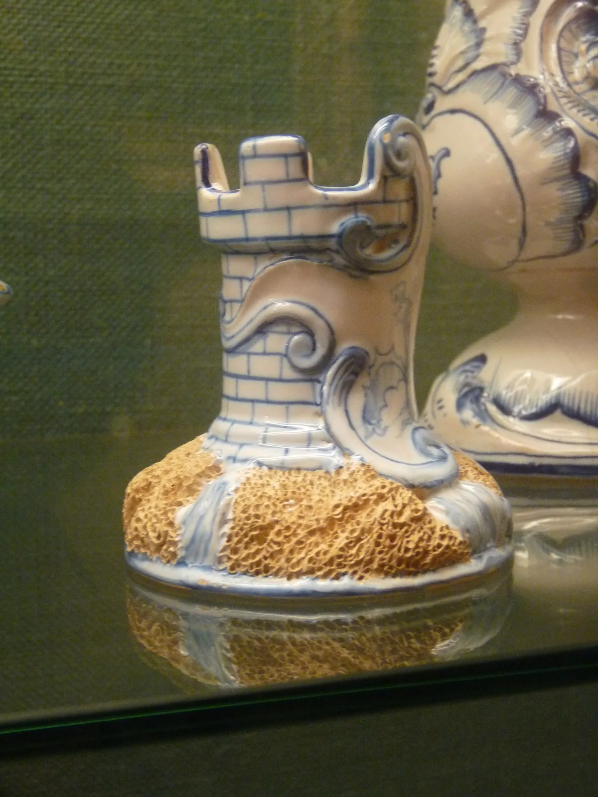 Blue and white faience match striker modelled as a castellated tower with scrolled foliage, set on an oval base half covered by a coarse buff abrasive patch