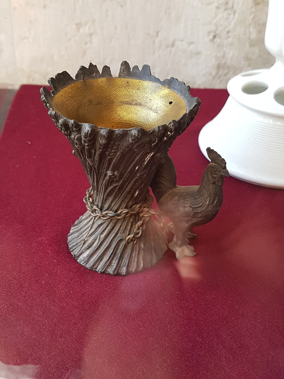 Cast white-metal match holder modelled as a bound sheaf of wheat with a gilded interior well, a cockerel standing at its side