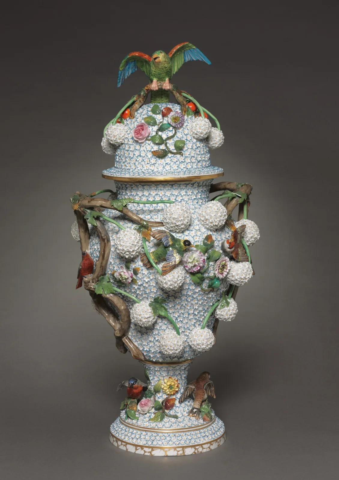 Covered porcelain vase encrusted all over with hundreds of small white applied blossoms, with modelled branches and coloured flowers around the shoulder and a bird perched on the domed cover