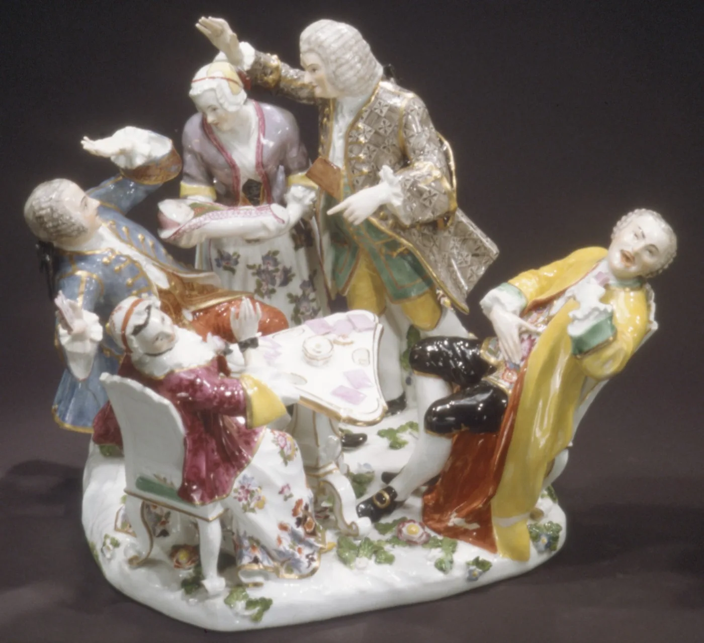 Crowded porcelain group of figures in eighteenth-century dress gathered around a reclining woman on a flowered base, painted in pale pinks, blues and yellows with gilt detail