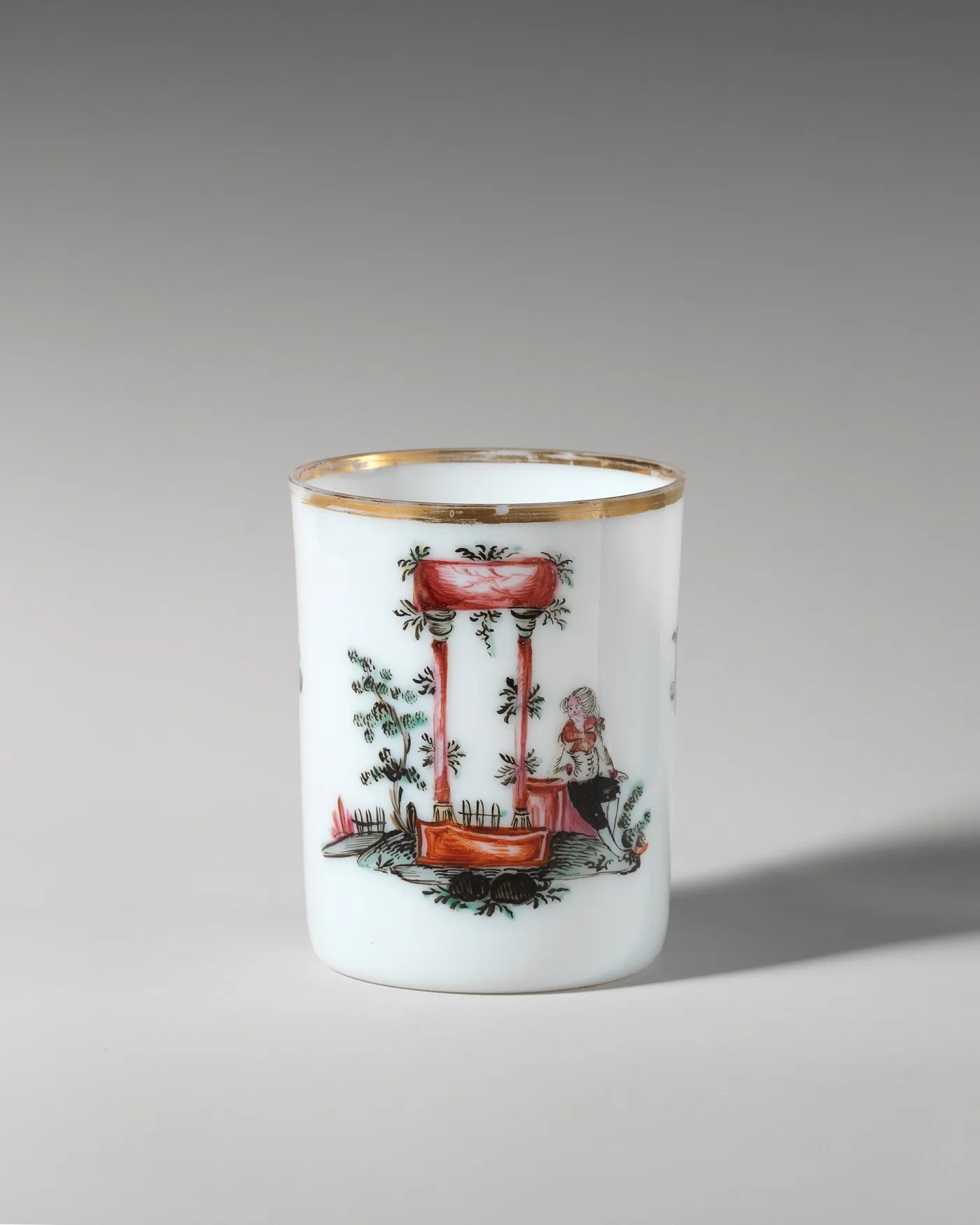 Cylindrical white glass mug painted with a red chinoiserie pavilion and a seated figure, with a gilt rim