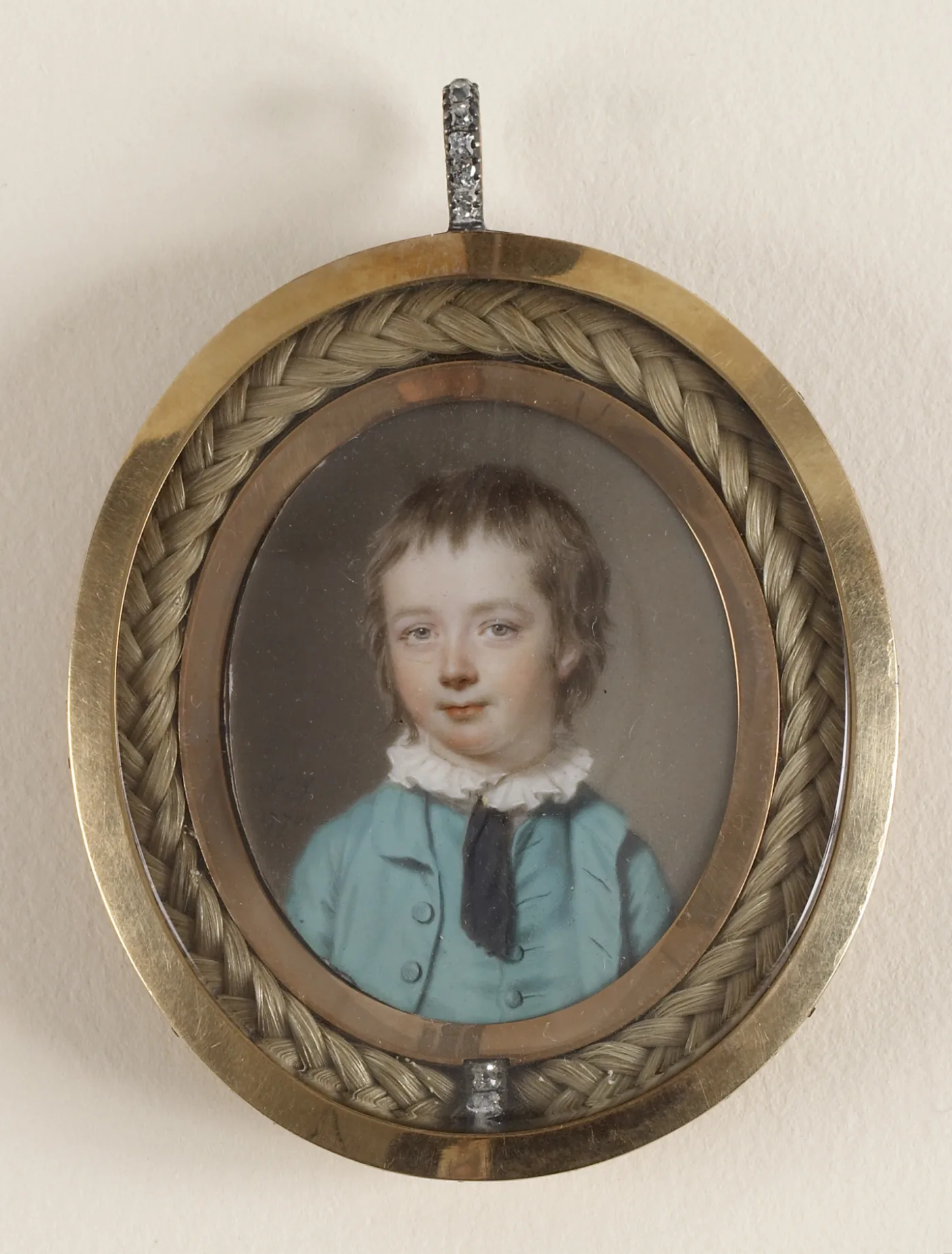 Portrait miniature of a boy in a blue coat by John Smart, set in a gilt pendant with a laurel border