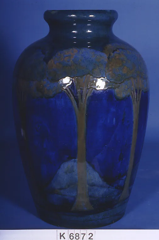 Dark blue baluster vase decorated with slender trees against a mottled blue and gold sky, photographed against a plain ground with a negative number strip below