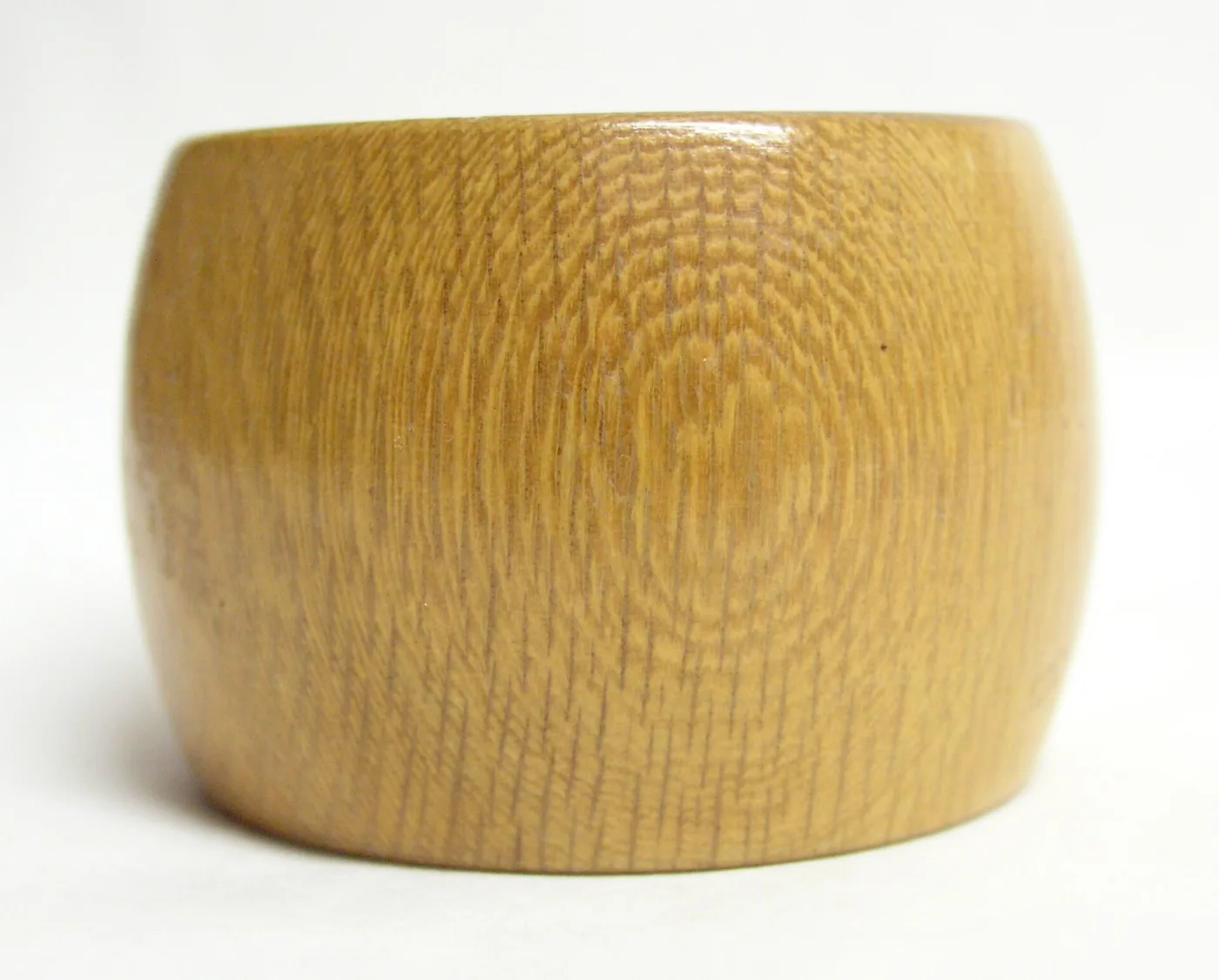 Plain turned pale hardwood napkin ring, barrel-shaped, with no decoration beyond the figure of the grain