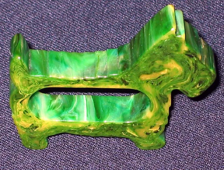 Napkin ring of green and yellow swirl-marbled plastic formed as a Scottie dog, the napkin opening cut through the body between the legs