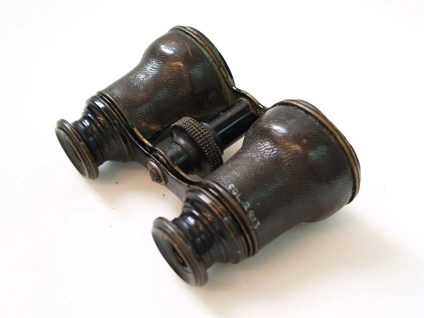 Opera glasses with dark grained leather covering the barrels, black turned eyepiece cups and a knurled metal focus wheel