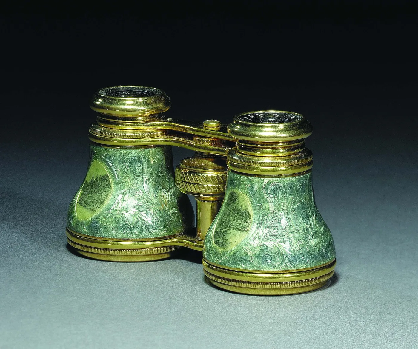 Gold-mounted opera glasses with translucent green enamel barrels showing engraved foliage and oval landscape panels