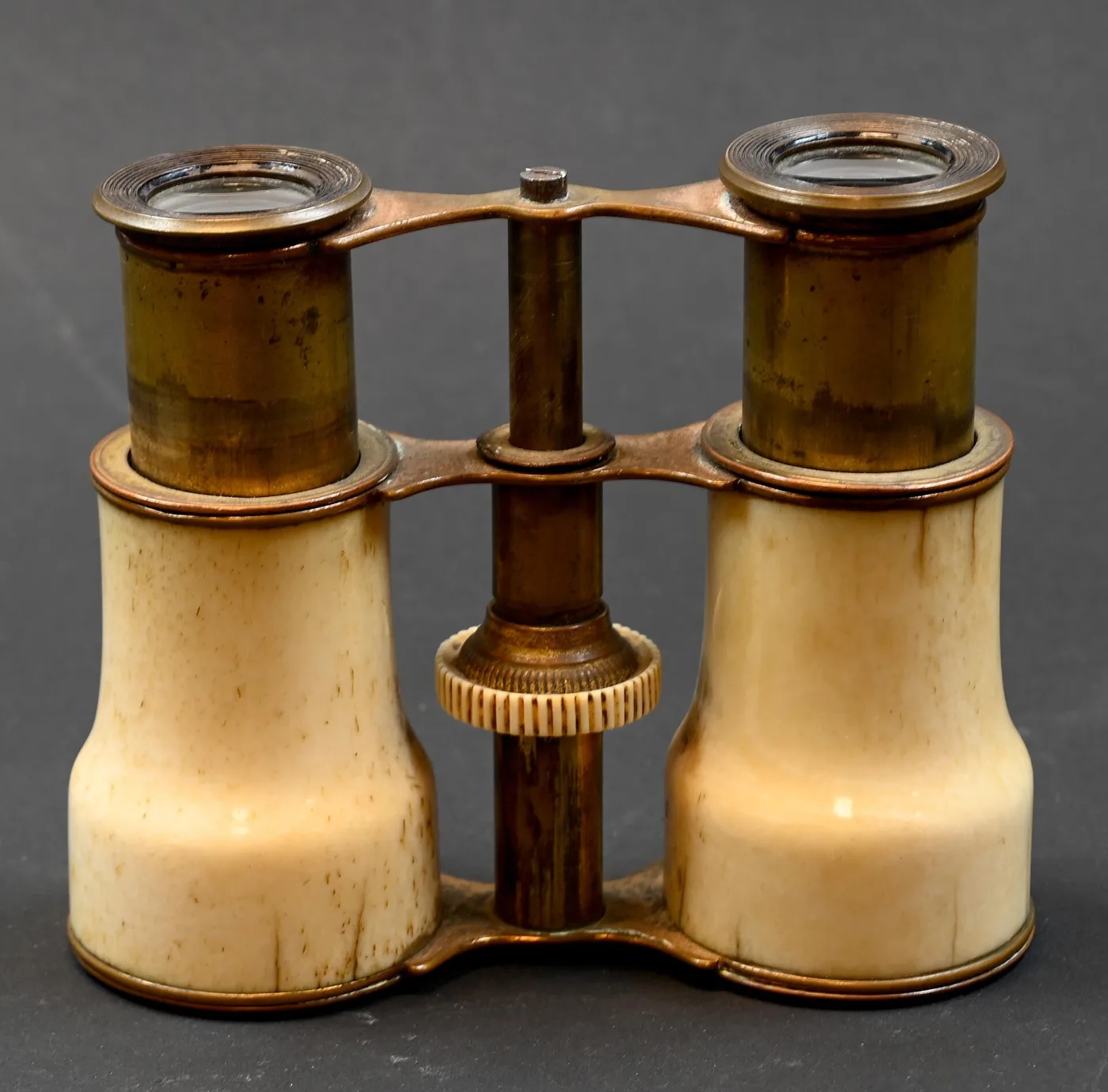 Bone-barrelled opera glasses seen end-on, with a knurled bone focus wheel on the central post