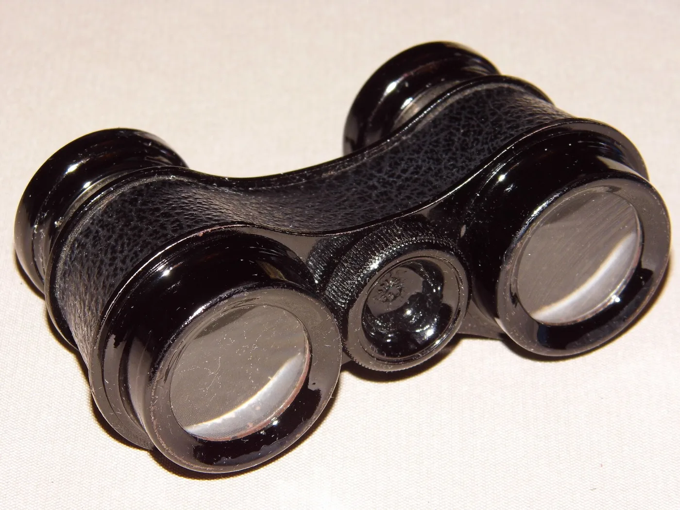 Black opera glasses with a pressed textured covering, glossy moulded eyecups and no visible mark