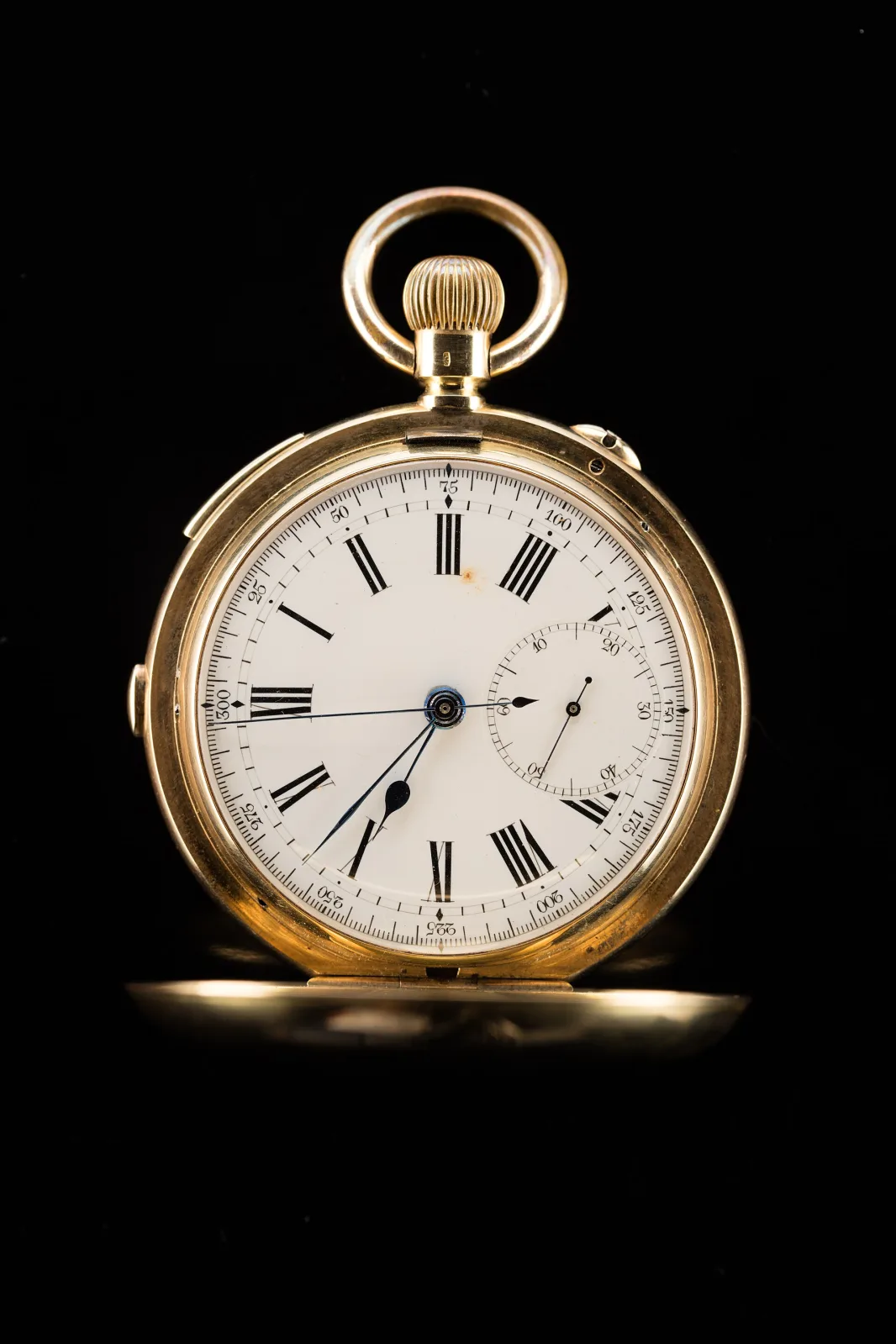 Gold pocket watch photographed against black, its hinged front cover swung open to show a white enamel dial with black Roman numerals, blued steel hands and a small seconds dial at six o'clock