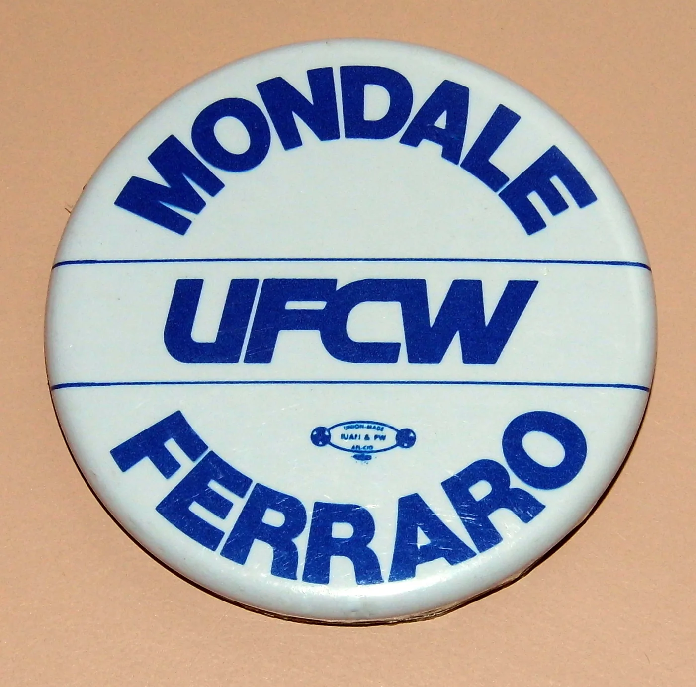 Round celluloid campaign button reading MONDALE FERRARO in blue on white, with the union initials UFCW across the centre and a small printed union bug beneath them