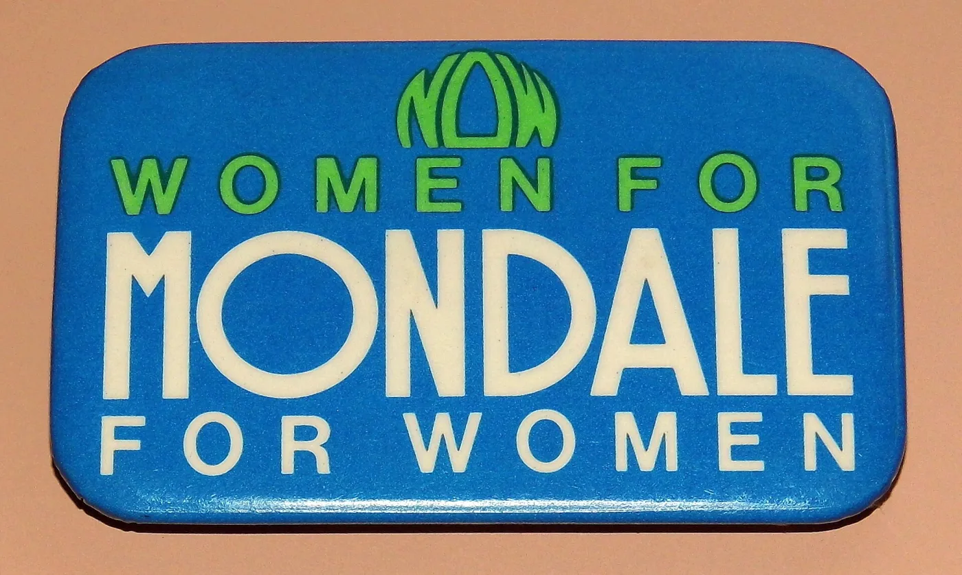 Rectangular lithographed metal campaign button with rounded corners, printed WOMEN FOR MONDALE FOR WOMEN in yellow and white on a blue ground with a green graphic above