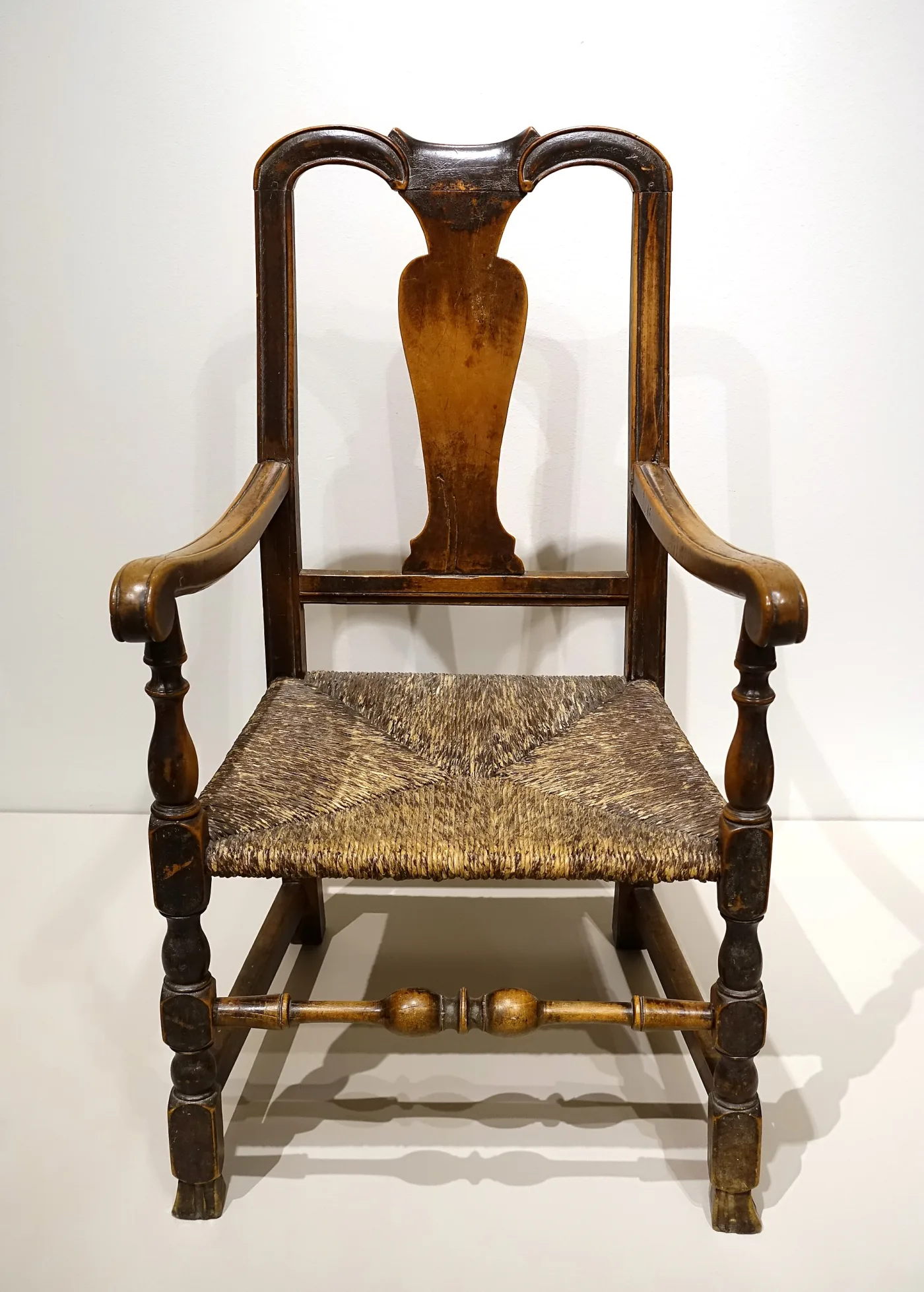 Rush-seated armchair with turned baluster legs, a block-and-baluster front stretcher and outward-flaring ribbed Spanish feet