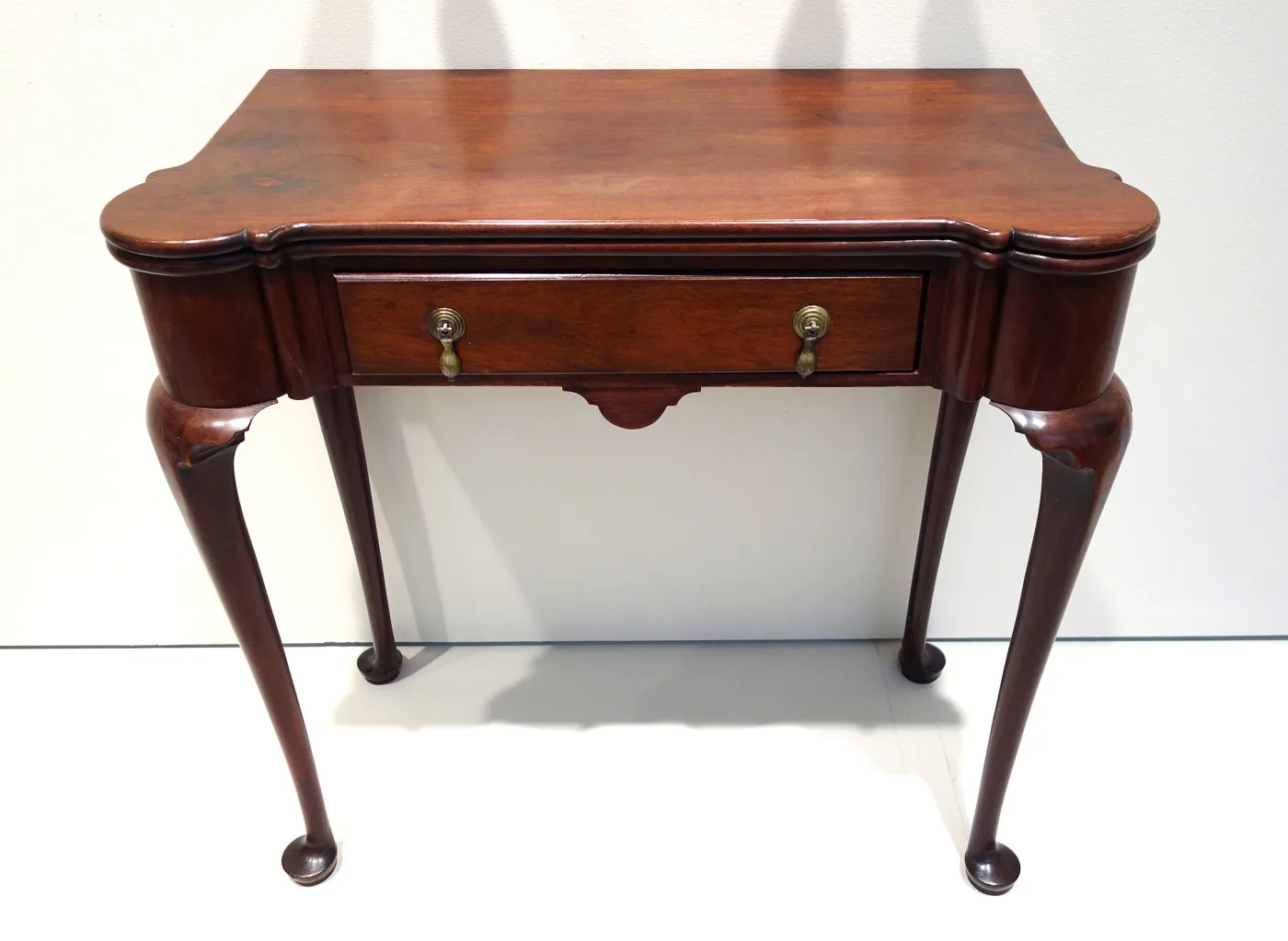 Mahogany card table with a folding top, rounded projecting corners, a single drawer and cabriole legs on pad feet