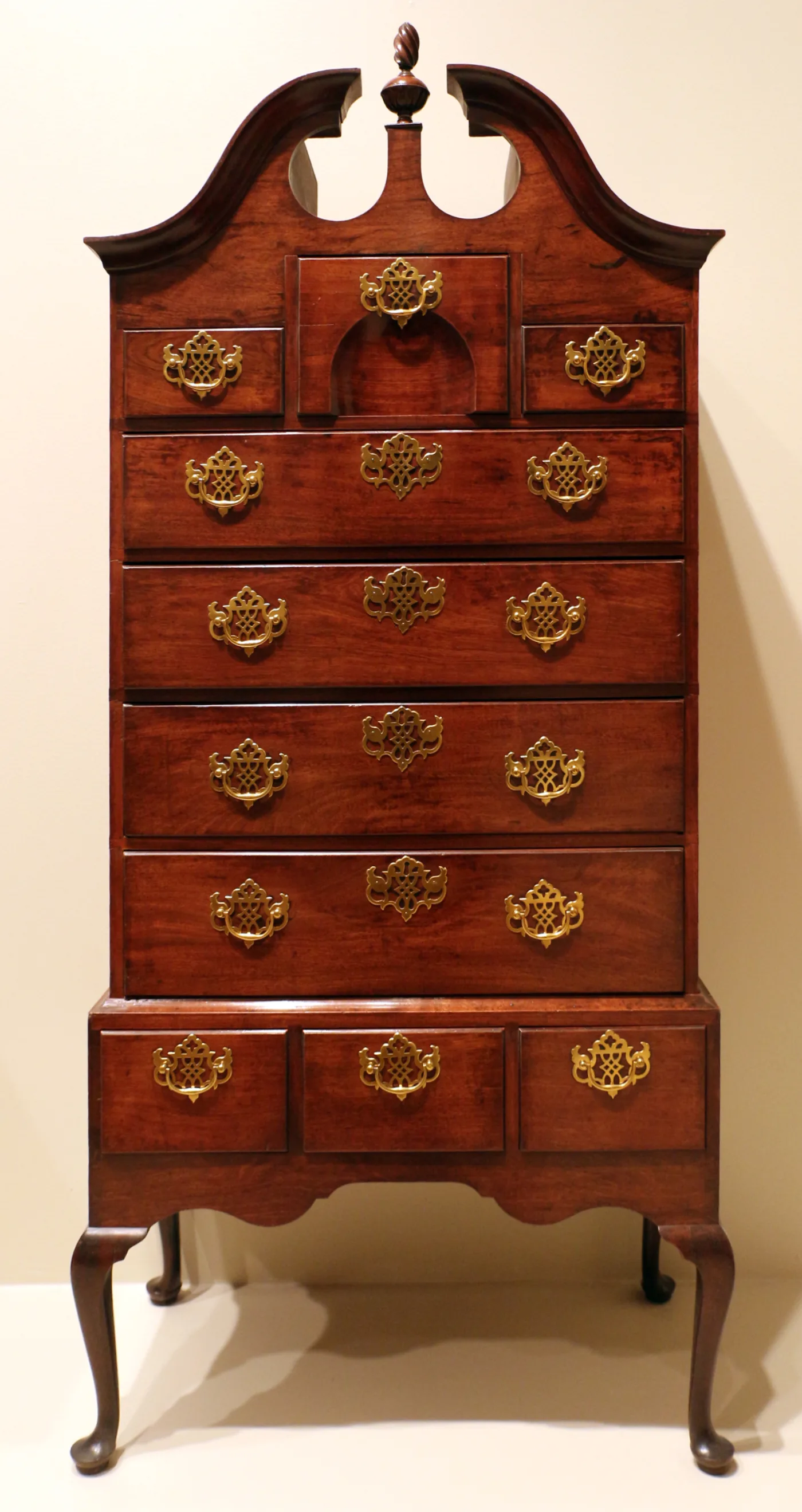 Tall high chest with a broken-scroll pediment and pierced openwork brass back plates and escutcheons on every drawer