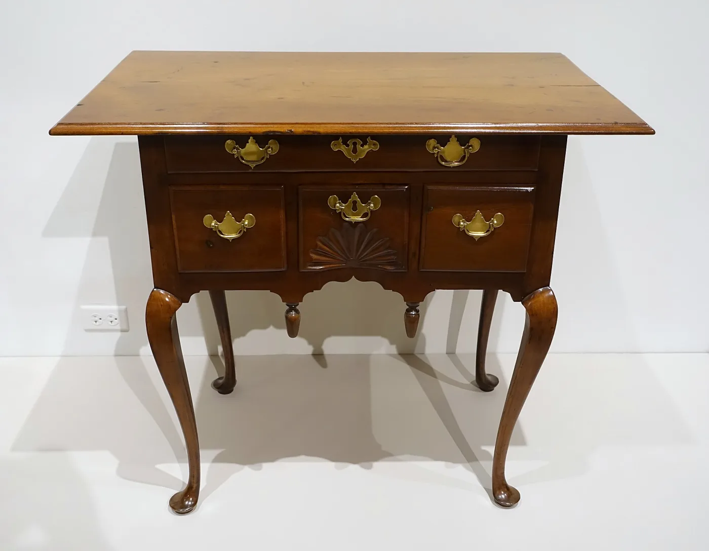 Cherry dressing table with a fan-carved centre drawer, a shaped skirt with two turned pendant drops and cabriole legs ending in pad feet
