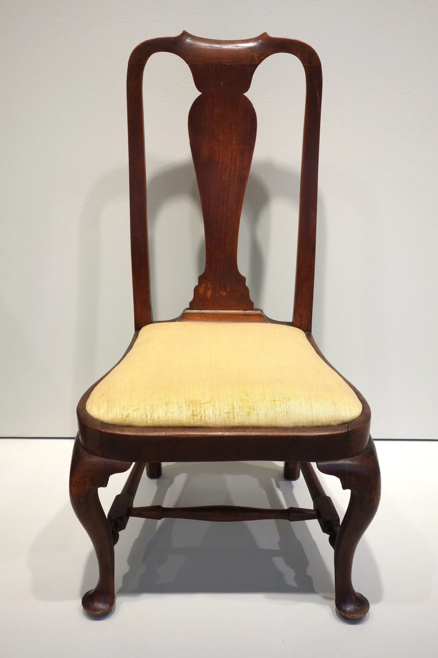 Walnut Queen Anne side chair with a curved yoke crest, solid vase-shaped splat, rounded compass seat and cabriole front legs ending in pad feet