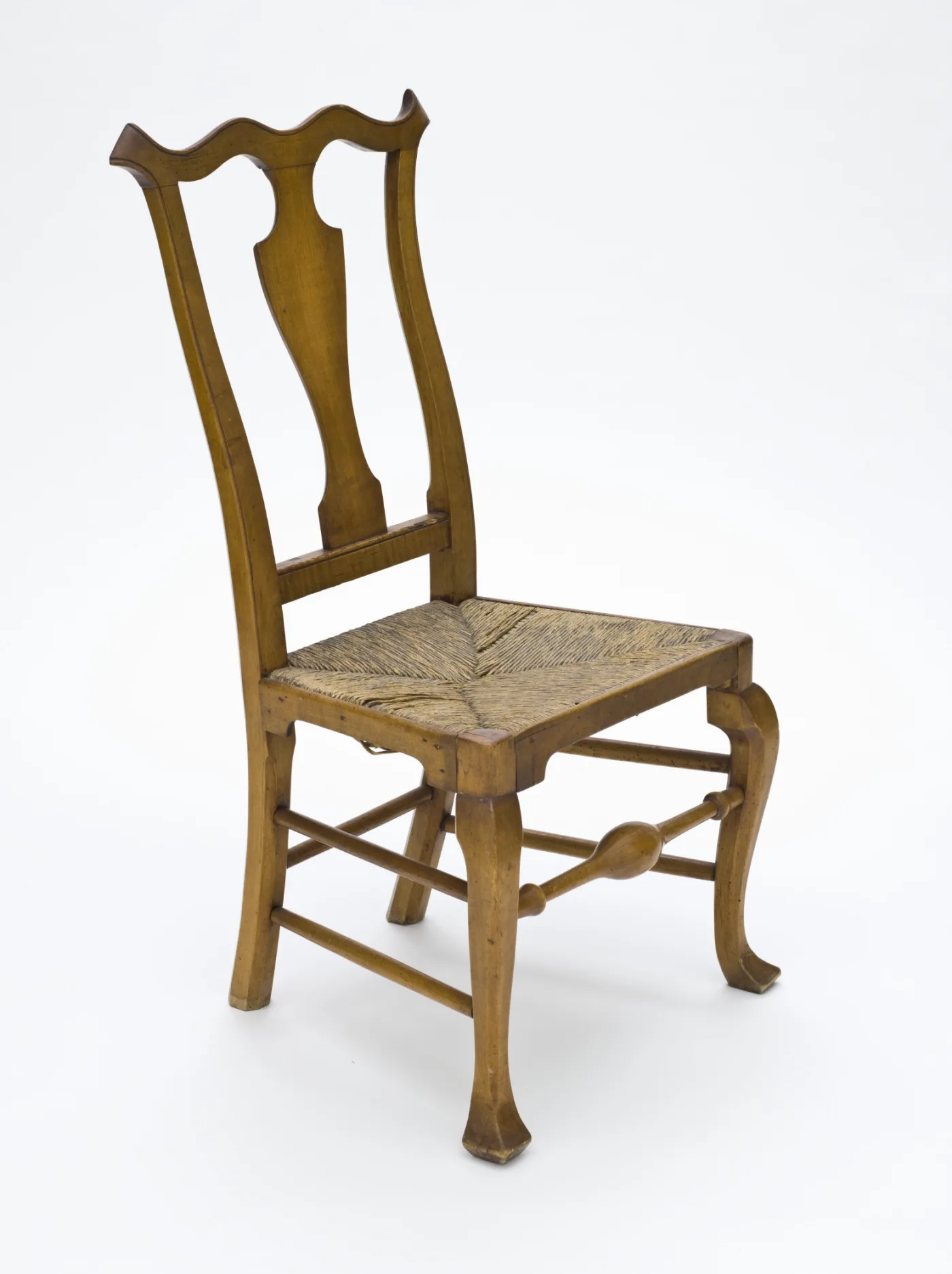 Rush-seated side chair with a shaped yoke crest, plain solid vase splat and cabriole front legs ending in elongated pointed feet