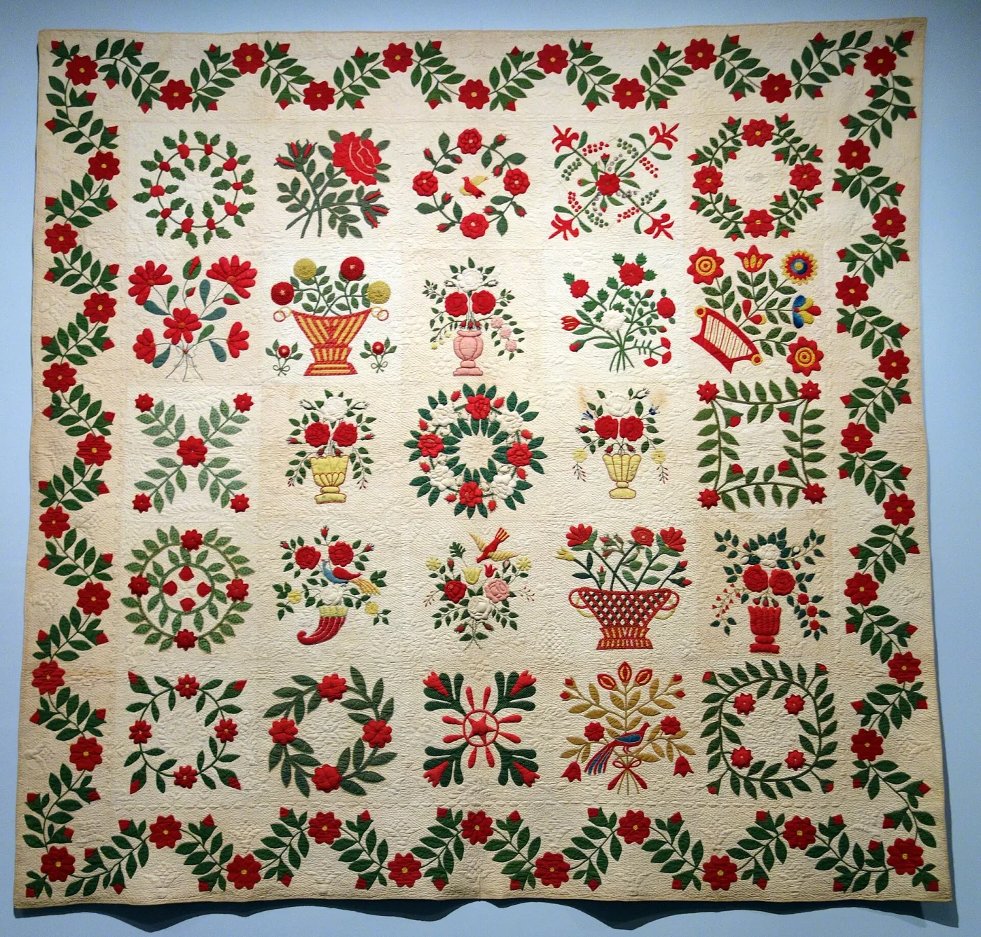 Album quilt of twenty-five white blocks, each appliqu&eacute;d with red flowers, green leaves, baskets and wreaths, surrounded by a red-and-green trailing rose border