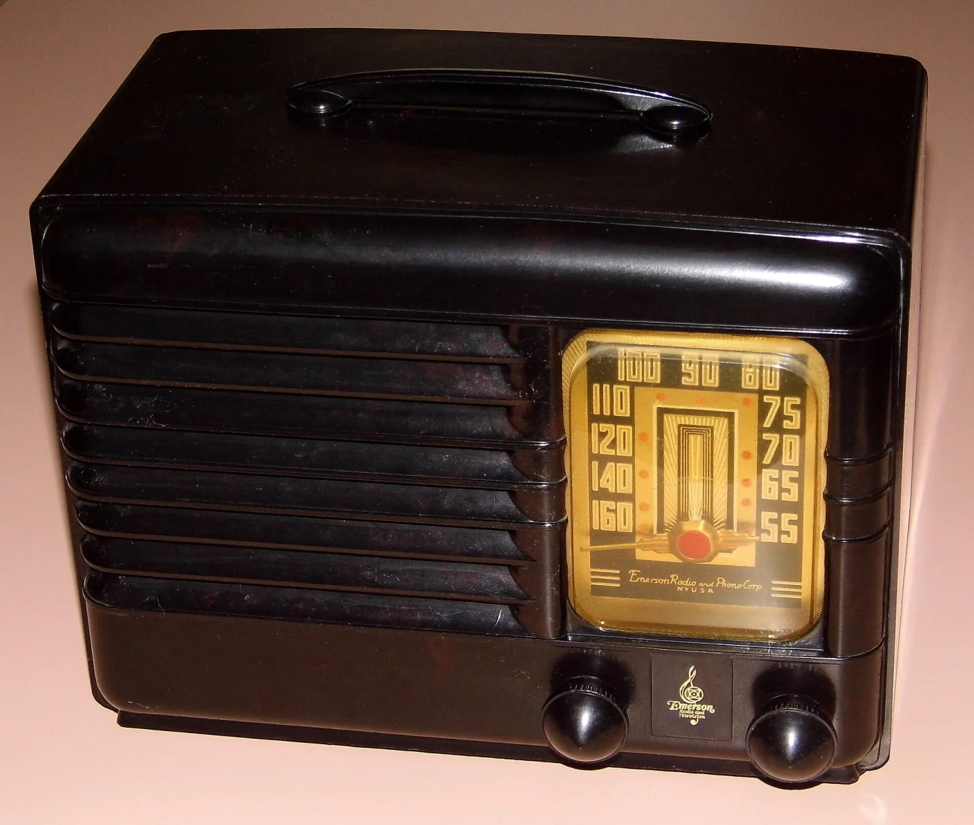 Dark brown moulded plastic table radio with a carrying handle, horizontal ribbed grille and a gold Art Deco dial