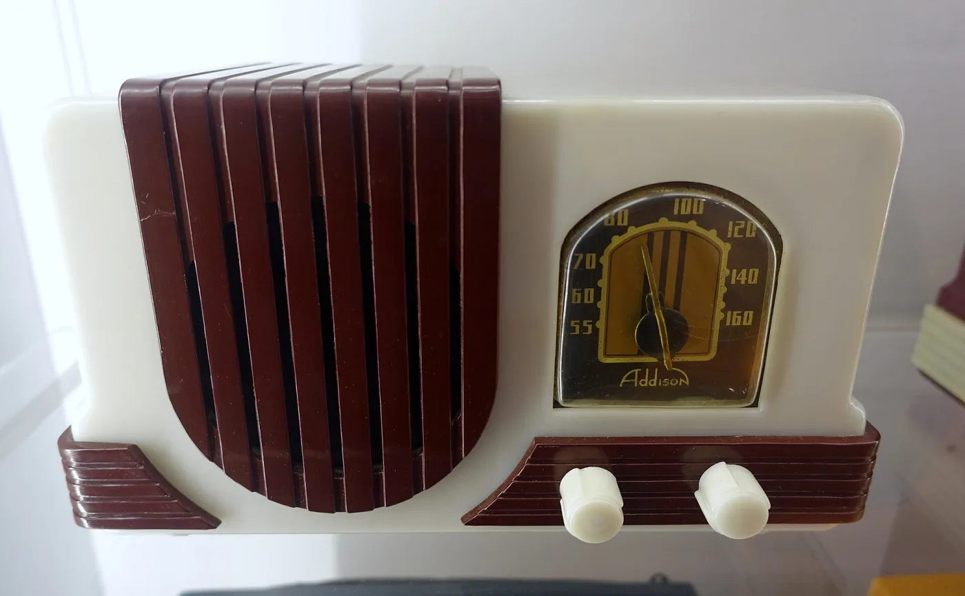 Cream plastic table radio with a maroon ribbed speaker grille, maroon knob plinth and an arched gold dial