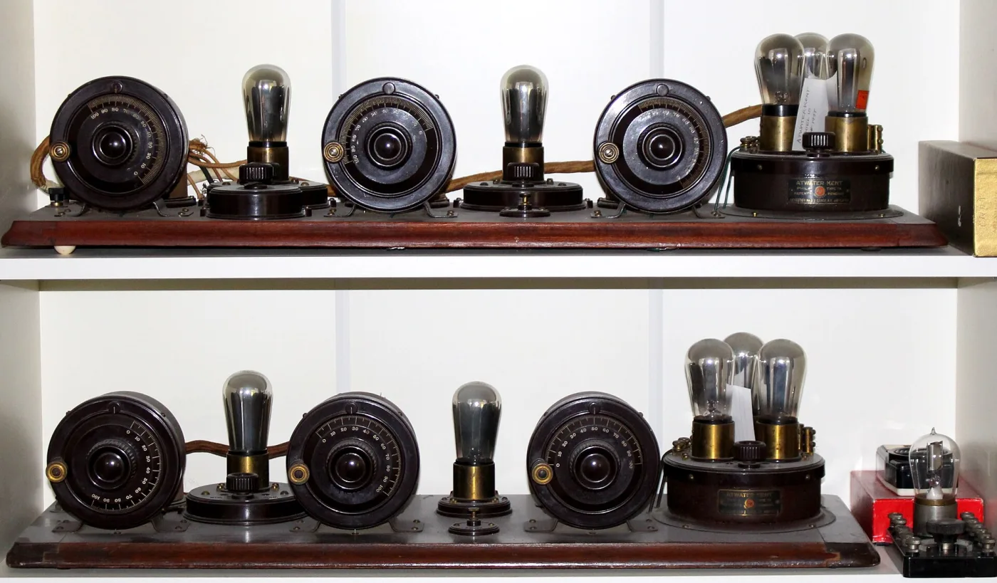 Two long wooden boards on shelves, each carrying three black tuning coils, exposed glass tubes in brass sockets and a strip of terminals