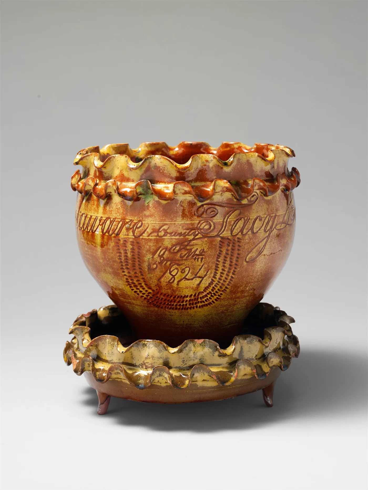 Redware flowerpot with a crimped rim standing in a matching crimped saucer, incised with script and the date 1824