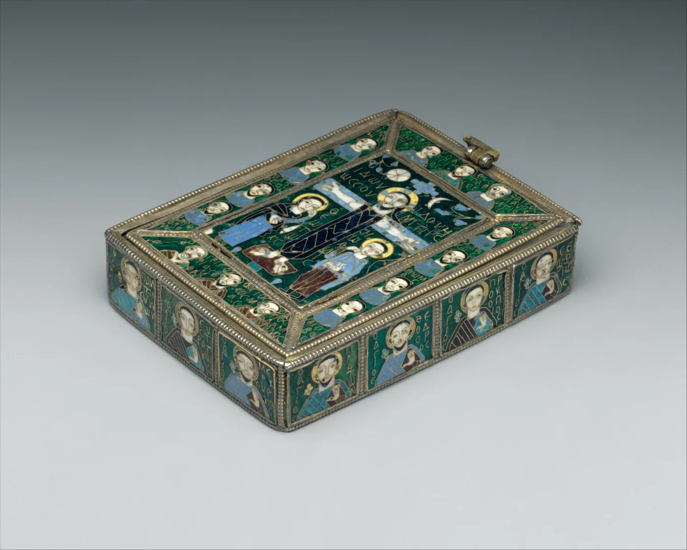 Small rectangular casket lid of gilded silver, its surface divided into panels of deep blue, green and white cloisonne enamel showing figures of saints in roundels around a central scene