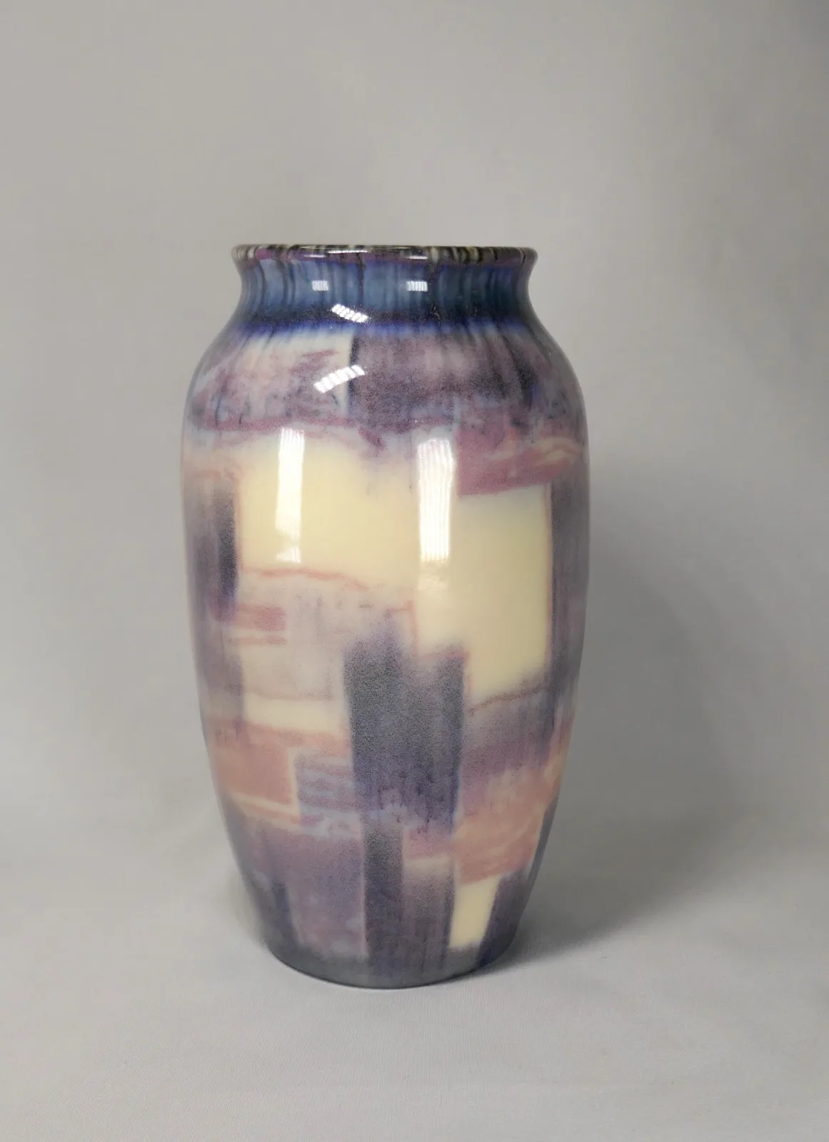Tall cylindrical vase decorated in broad vertical bands of mauve, cream and grey-blue with stepped geometric blocks, under a soft semi-matte glaze