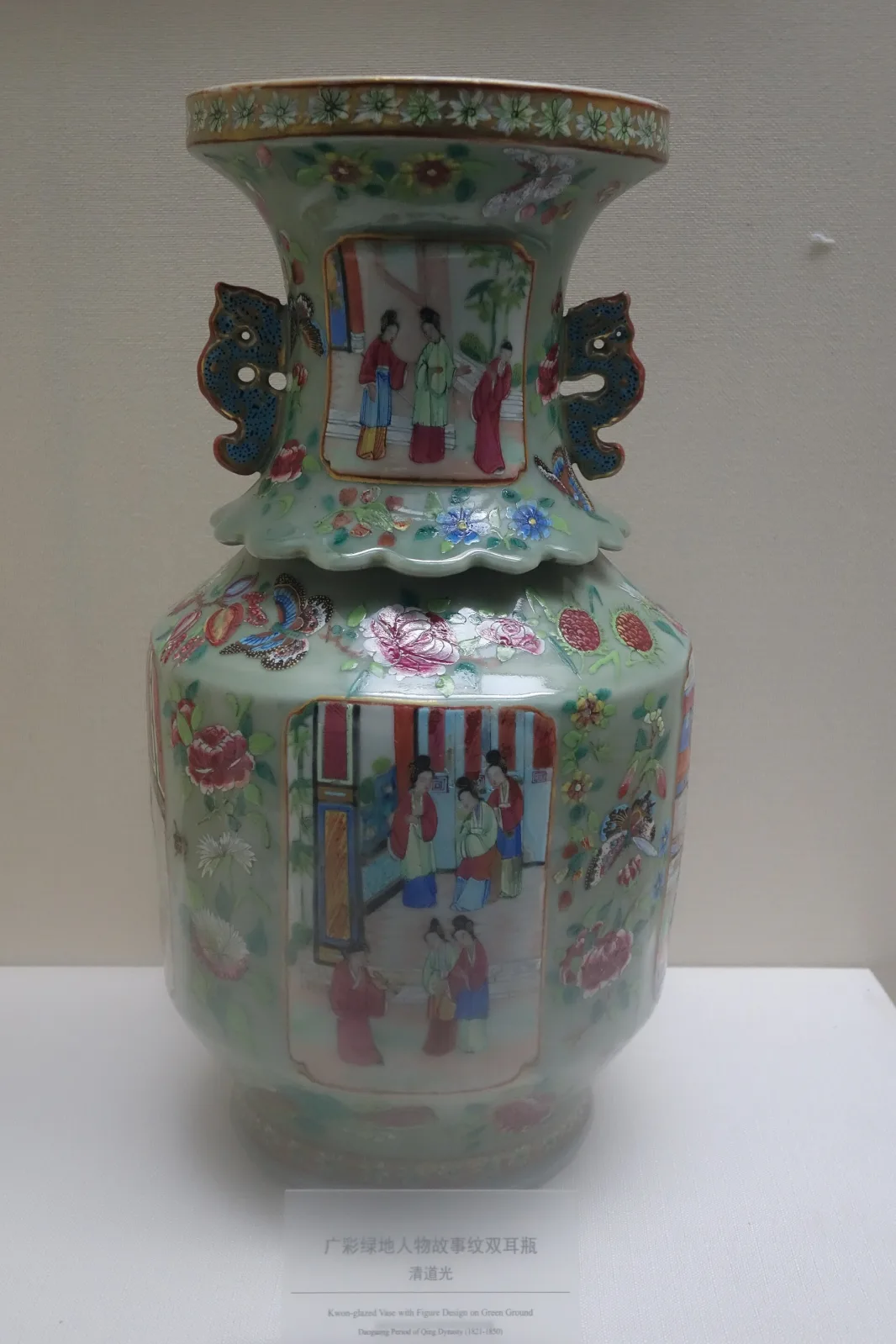 Qing Daoguang period Cantonese enamelled vase with two applied handles, its body covered in a green ground with white reserved panels holding groups of figures in pink and blue robes