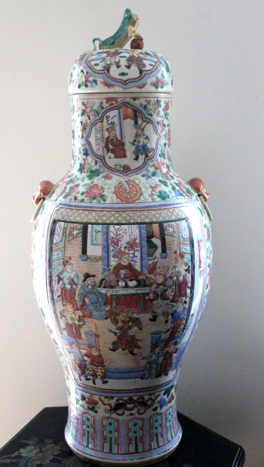 Nineteenth century Canton famille rose baluster jar with its original domed cover and seated lion finial, decorated with figure panels on the body and neck over a dense pink and green floral ground
