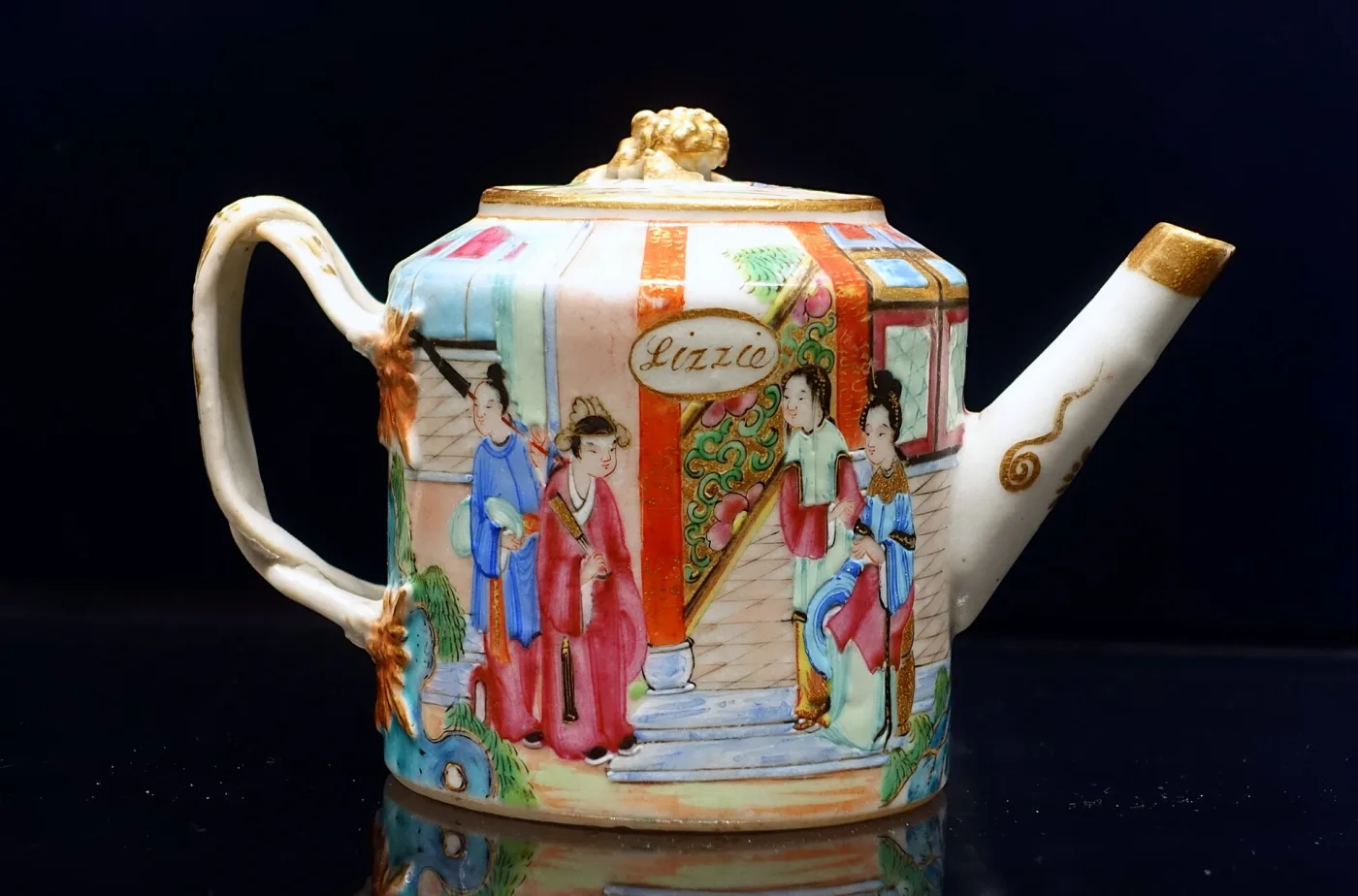 Miniature Chinese export teapot of 1865 to 1870 with figure panels in gilt frames, a gilt lion finial, and a cartouche carrying the name Lizzie in gilt script
