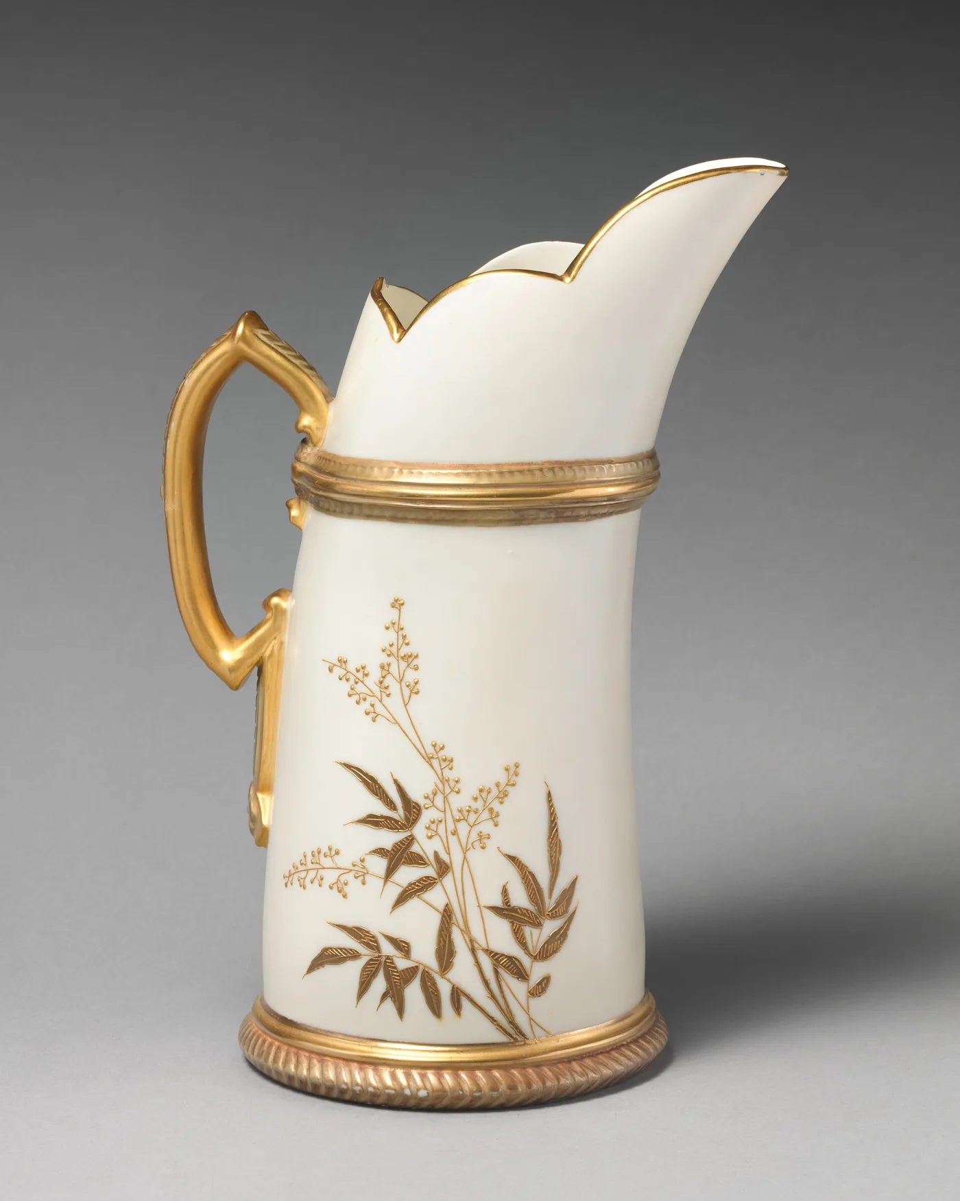 Tall ivory-coloured porcelain ewer with a shaped spout, a gilded handle and raised gold flowering branches across the body