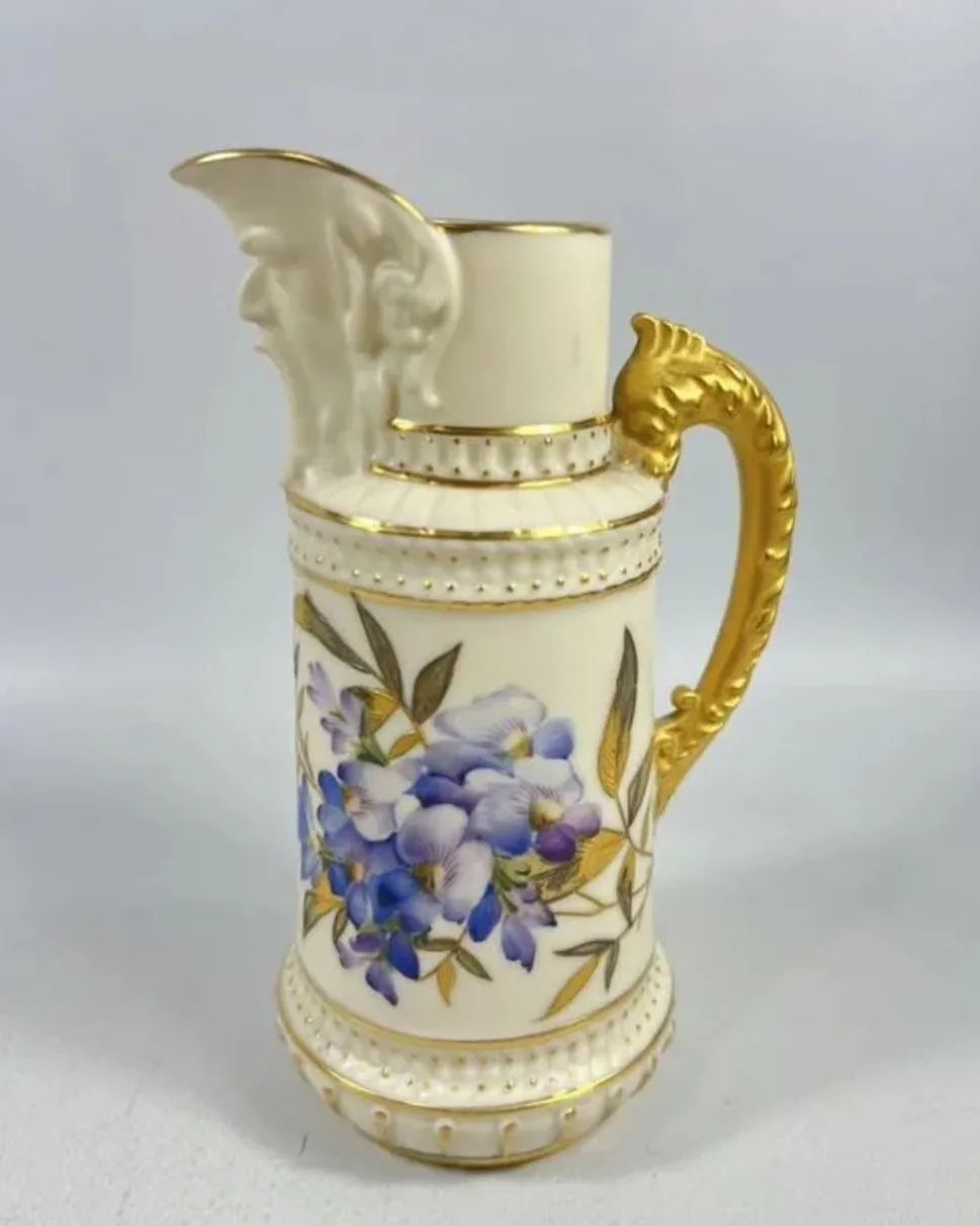 Tall cream-coloured jug with a bearded face moulded beneath the spout, a gold handle, beaded gilt bands and painted blue and purple flowers